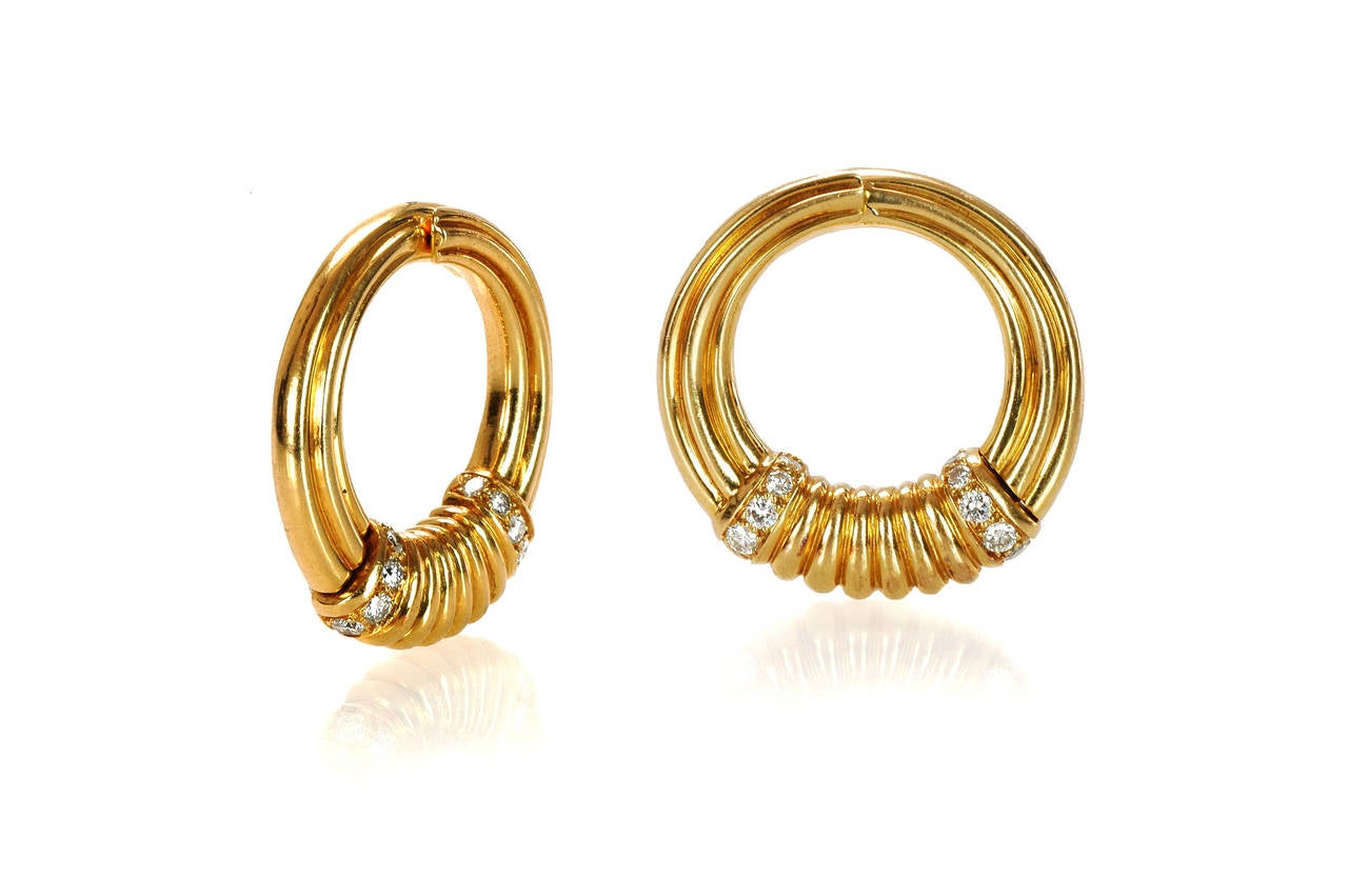 The circular hoops with reeded texture, centering fluted plaques flanked by domed rows of circular-cut diamonds (approximately 1 carat total weight), hinged for easy dressing, they turn nicely along the cheek creating the illusion of a closed