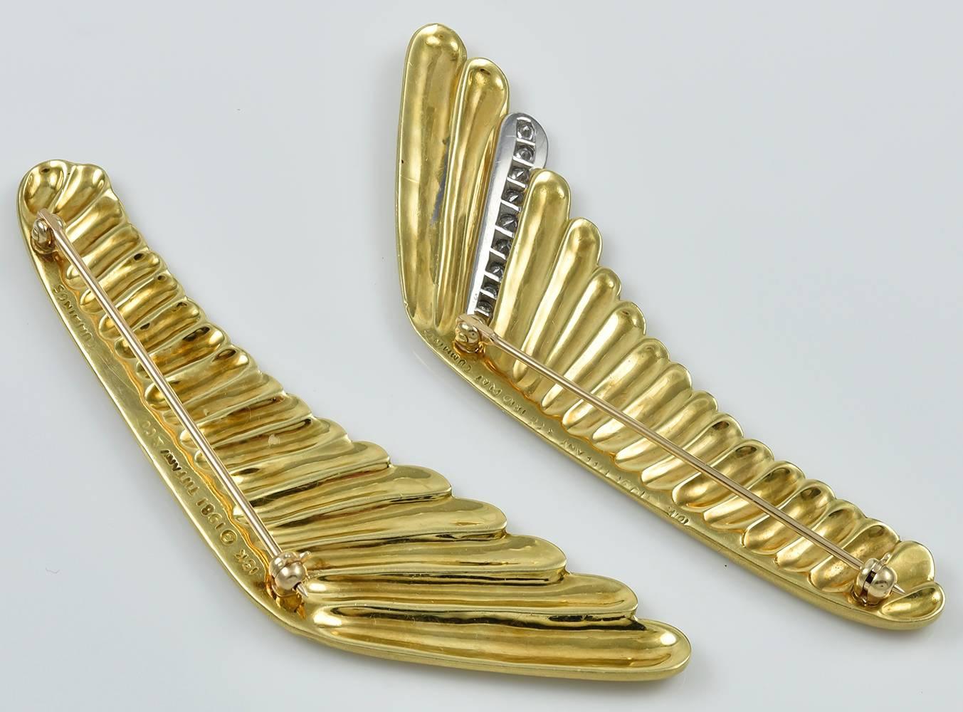 Two matte-finish yellow gold wing pins, worn together to great effect, one with diamond feather accent mounted in platinum for contrast, signed TIFFANY & CO CUMMINGS 18K IRID PLAT design copyrighted 1981, long single hinged pin backs with safety