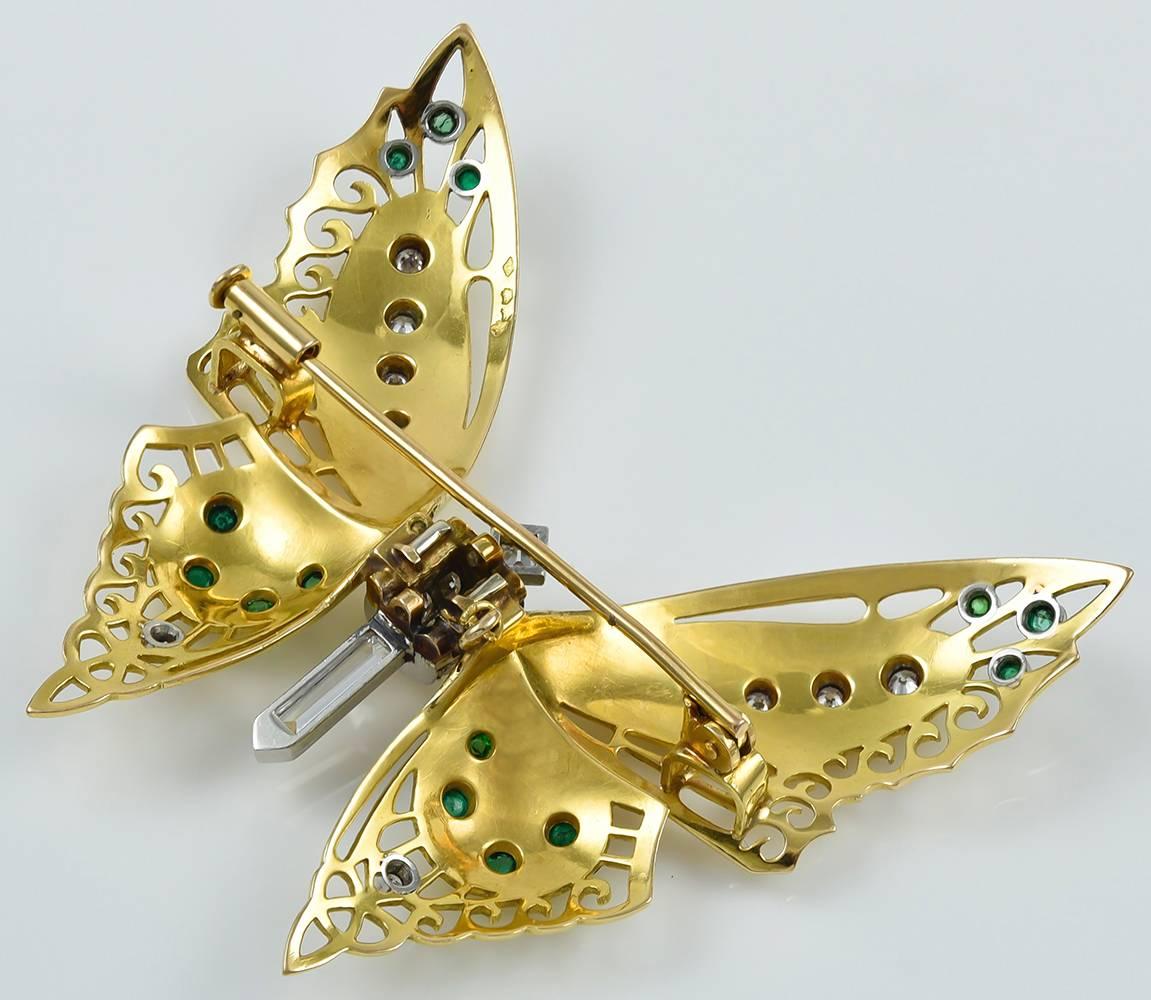 The polished 18kt yellow gold pin realistically designed as a butterfly, with delicate pierced wings accented with circular-cut diamonds and cabochon emeralds (25 diamonds weighing approximately 1.50 carats total), French maker's mark and French