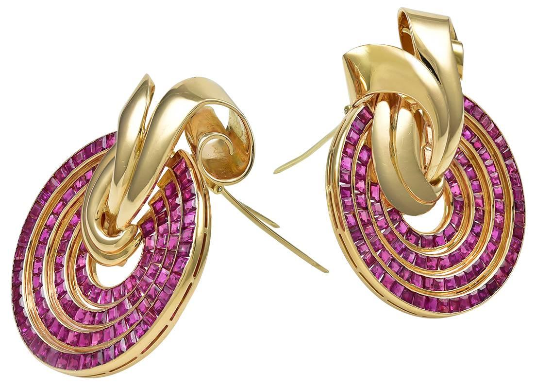The large, circular clips designed as four concentric circles like a target, set with square-cut rubies (app. 12 carats total) a lively raspberry pink color, enhanced with polished yellow gold ribbon scrolls, hinged double-pin clip backs and