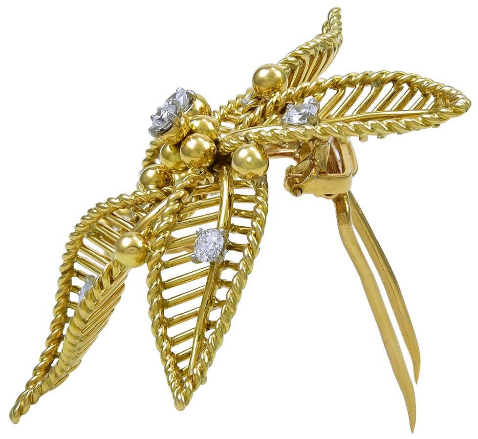 The brooch realistically designed as a flower head, its five scrolling petals executed in polished and twisted gold wire, enhanced here and there with gold boules and white circular-cut diamond accents (7 stones weighing approximately 1 carat