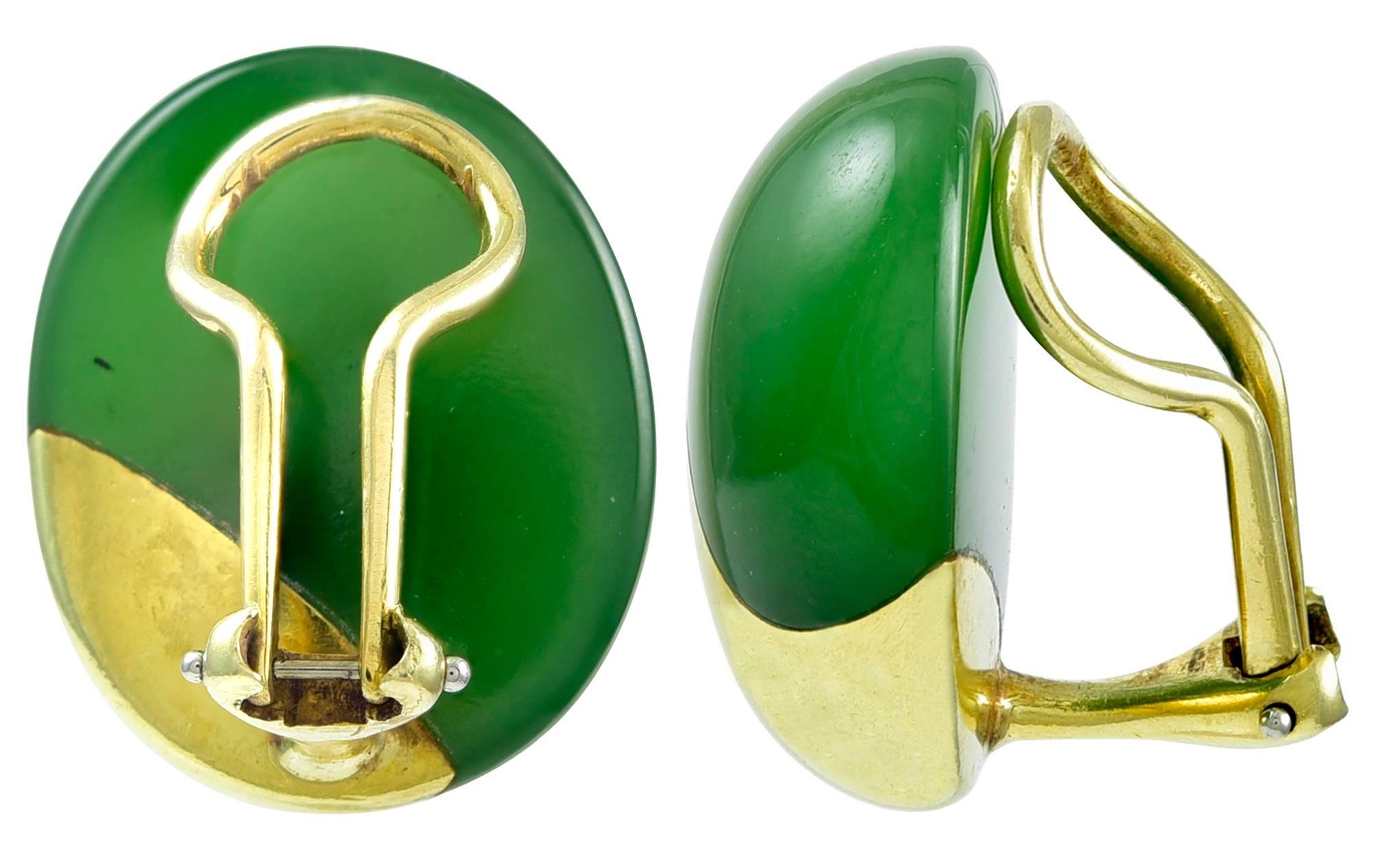 Soft oval shapes carved from nephrite jade and inlaid asymmetrically with burnished yellow gold designs, omega clip backs, unsigned, with scratch inventory numbers like those of Tiffany & Co jewelry, measuring approximately 7/8 inches high, weighing