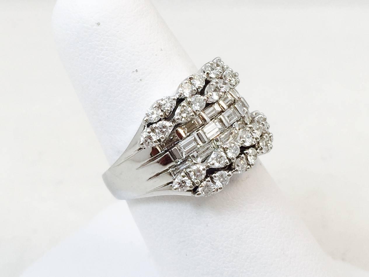 A major bling statement!  Wear as a cocktail ring, right hand ring or a stunning wedding band!  Fabulously crafted in 18 karat white gold, this ring features three center rows of bar set white straight baguette diamonds.  Top and bottom design has