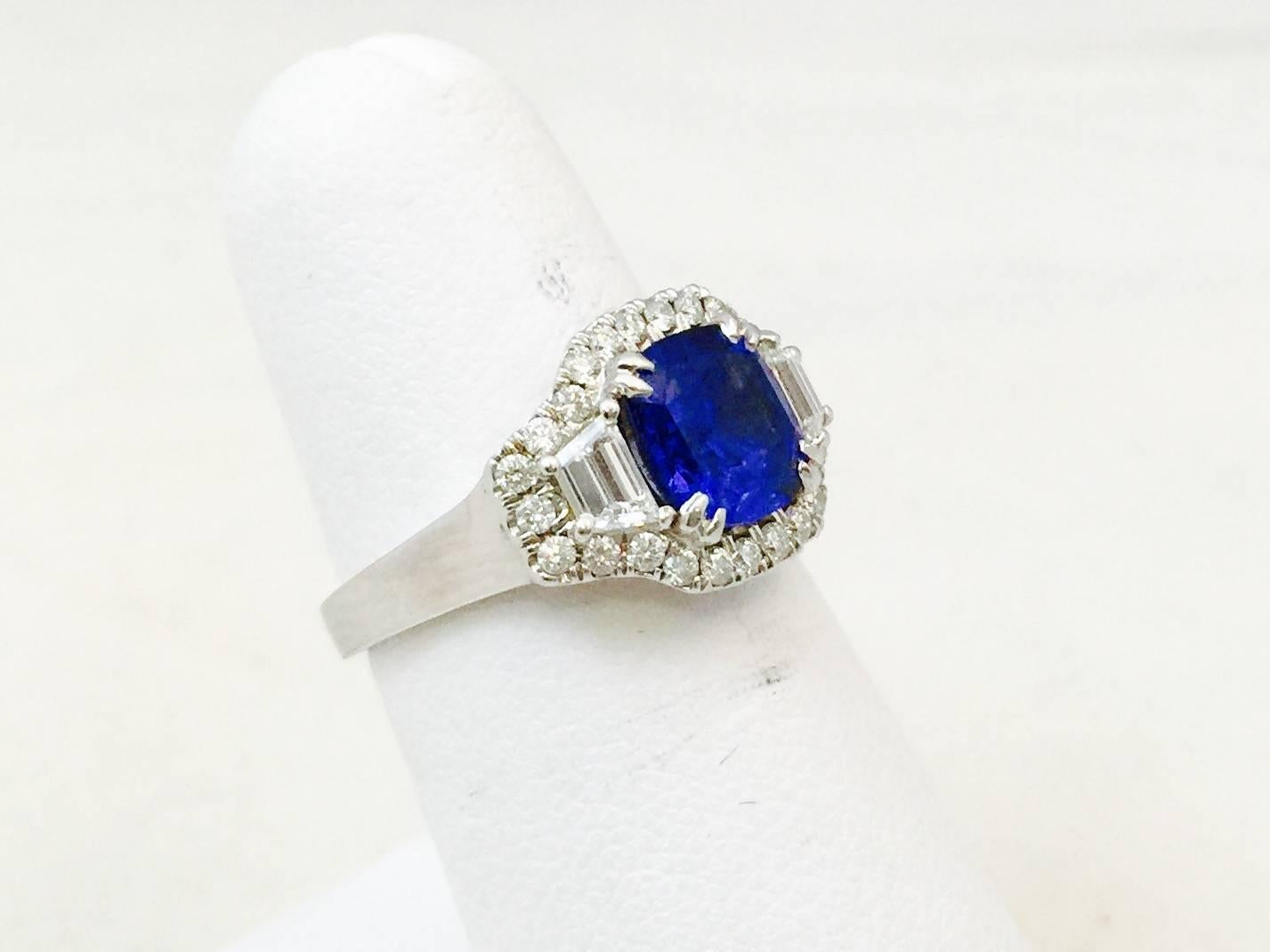 Meticulously crafted in 18 karat white gold boasting a magnificent Cushion Cut Ceylon Sapphire weighing 2.40 carats. Enhanced on each side is a Trapezoid cut white diamond with 0.45 carats total having F color, VS clarity.  Complimented by a