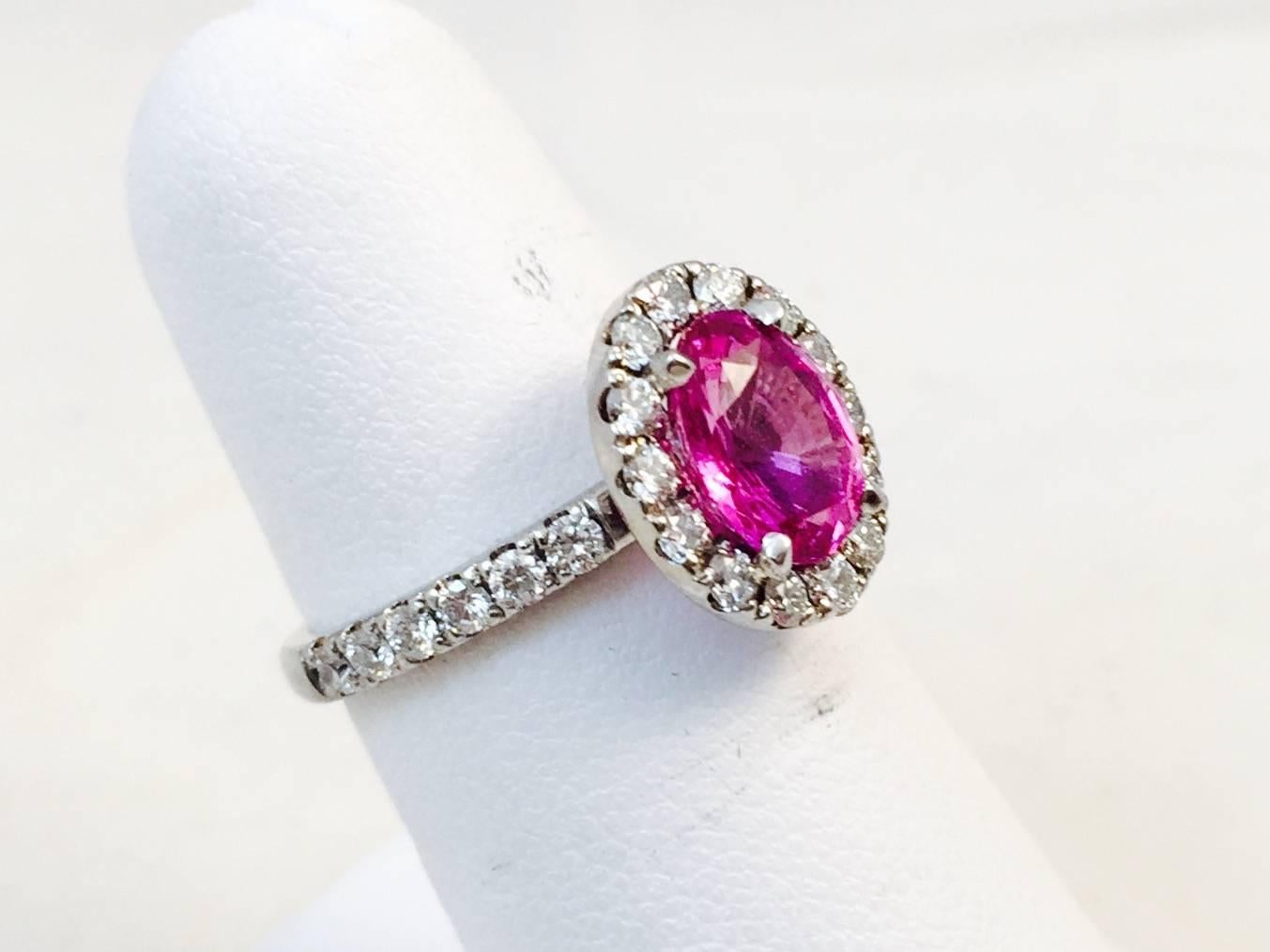 Carefully crafted in 18 karat white gold, this magnificent ring features an oval Pink Sapphire weighing 2.25 carats.  This gorgeous stone is enhanced by a halo of white brilliant cut prong set diamonds extending half way around the shank.  Diamonds