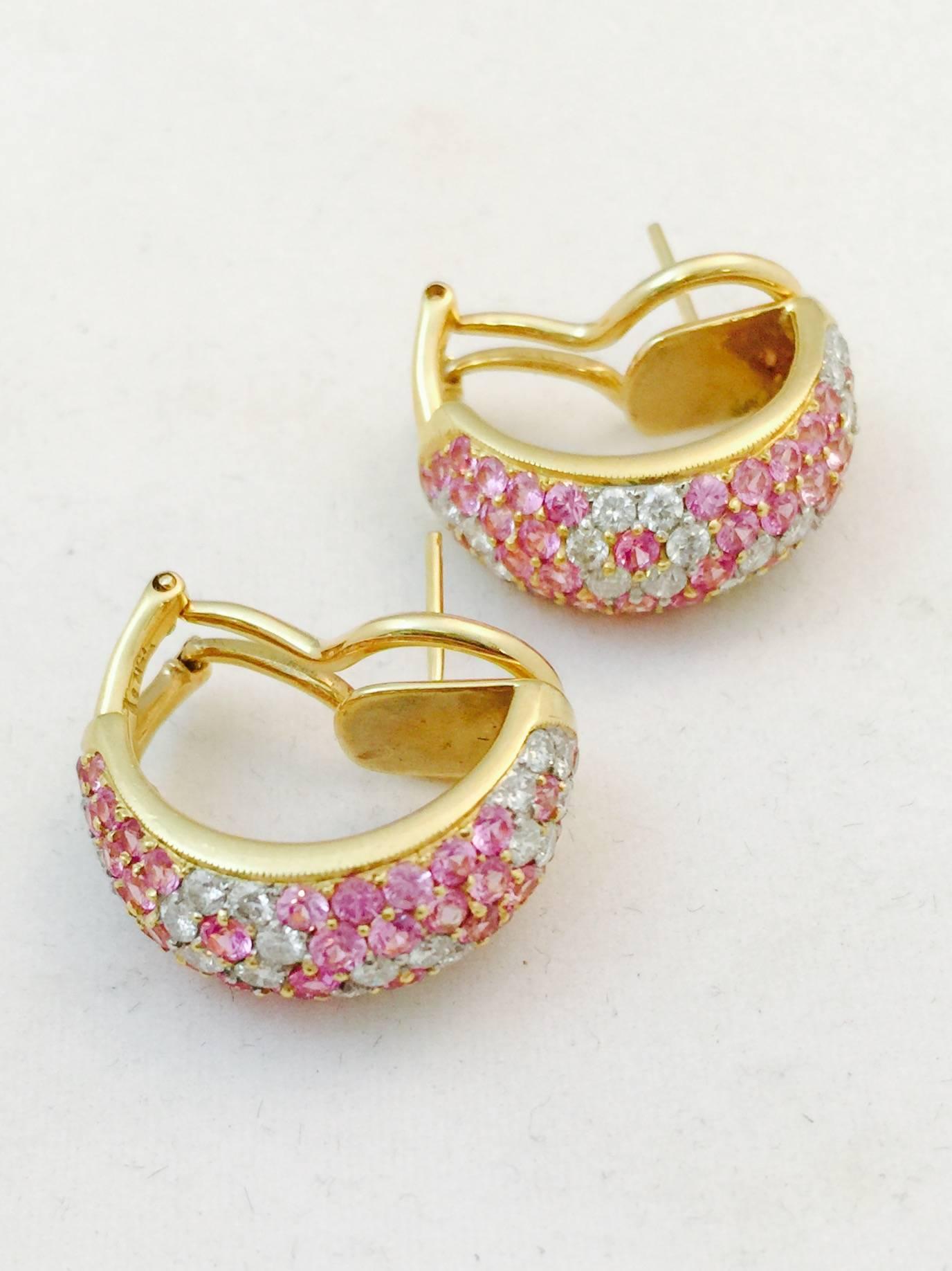 Distinctly feminine and meticulously crafted in 18 karat yellow gold, these Omega back pierced earrings are 1/2 hoop design.  Encrusted in round, faceted, perfectly matched pink sapphires and white brilliant cut diamonds that create a floral design.
