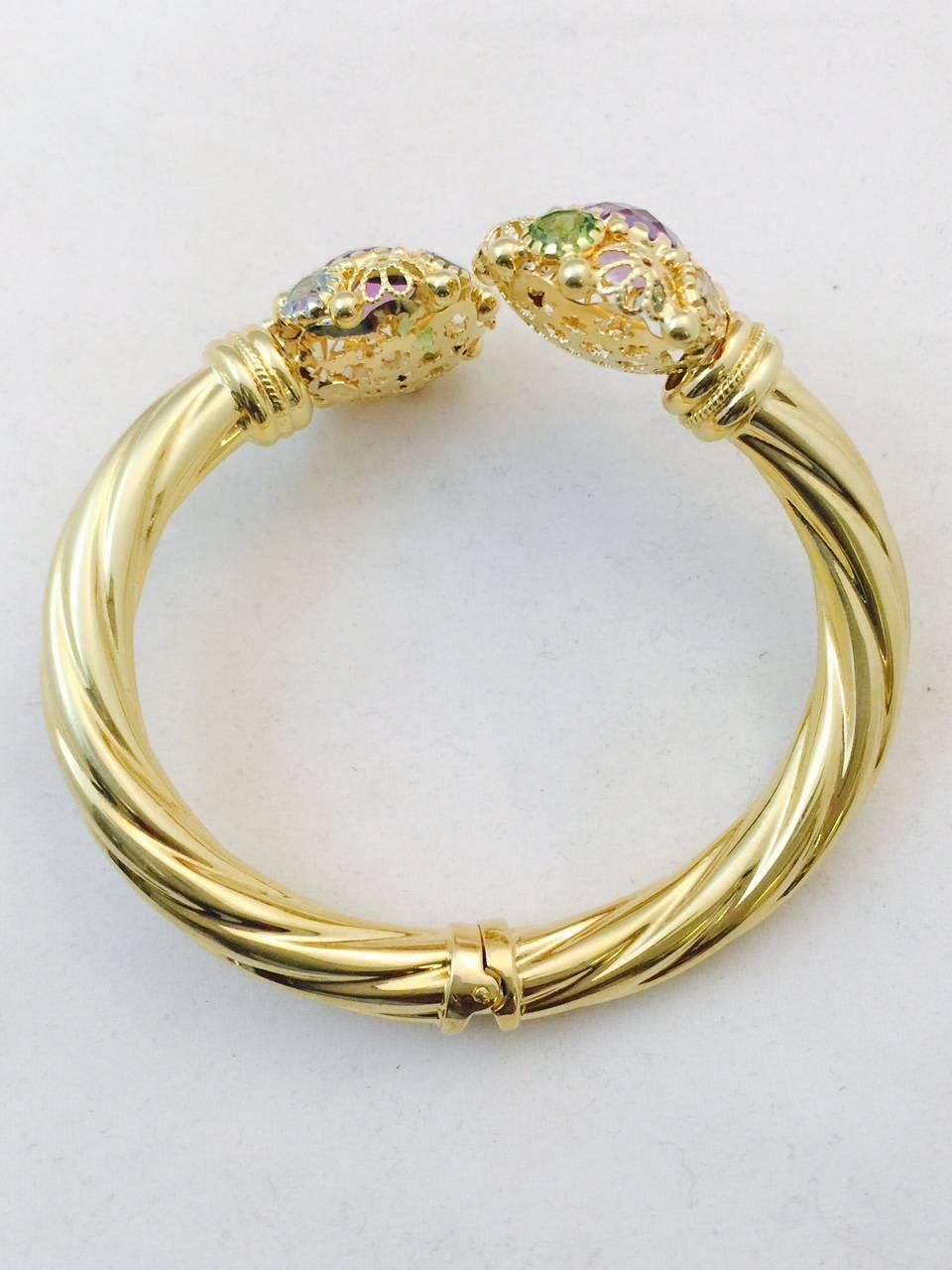 Meticulously crafted in 18 karat yellow gold, this fabulous by-pass design hinged bangle bracelet is certain to please the most discerning fine jewelry lover!  Each bangle end boasts a circle with fancy open gold work and perfectly matched pie crust