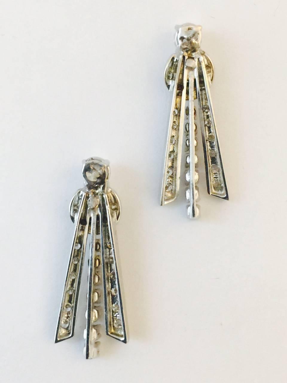 Destined to become your signature earrings!  From jeans to formal, these pierced earrings are fabricated in 14 karat white gold.  Top is a classic brilliant cut diamond, followed by another brilliant cut diamond, both prong set.  A half moon of