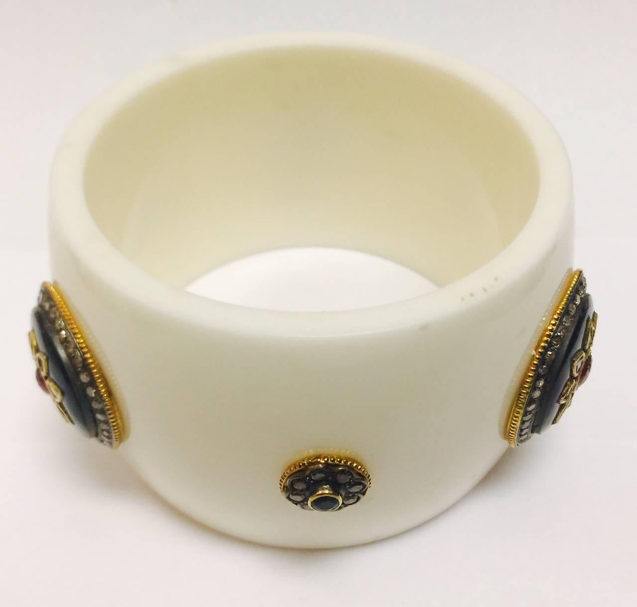 Retro yet modern!  This ivory color bakelite cuff features different size fittings containing single cut diamonds, macle diamonds and fine enamel work.  Fittings are finished in ribbed borders.  A ruby, a pink tourmaline and faceted onyx grace the