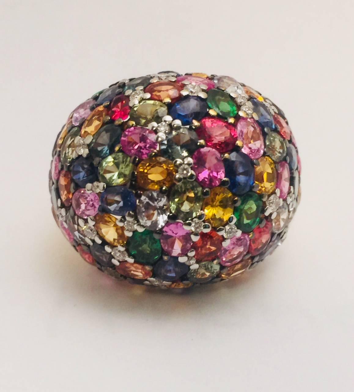 Sparkle more than the lights!  Fabricated in 18 karat yellow gold, this dramatic dome ring is encrusted with every color sapphire imaginable!   Each oval, faceted sapphire shares prongs for a seamless appearance.  Impressive combined total weight of