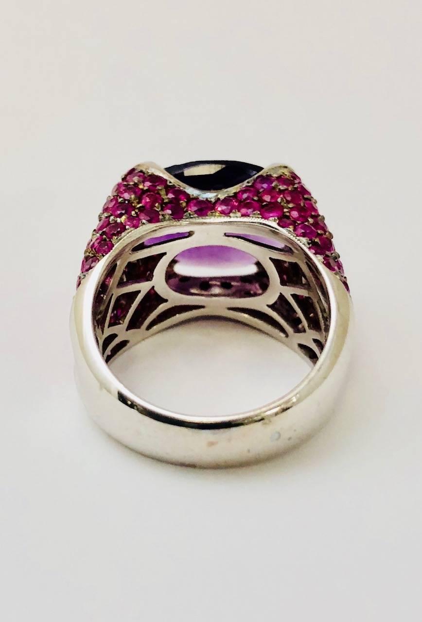 Made in 18 karat white gold, this fantastic ring features an East West 4 prong set oval, checkerboard faceted deep purple Amethyst.  All four sides are encrusted in rosey pink sapphires.  Color combination is absolutely stunning!  Amethyst has a