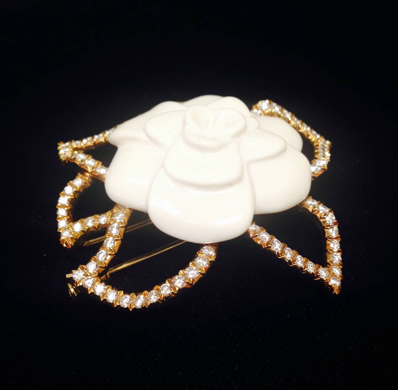 Simply stunning Chanel camellia crafted from 18K yellow gold and ceramic is a collector's dream!  Worthy of Chanel herself, this magnificent piece incorporates 95 dazzling white diamonds to outline this elegant flower's leaves.  Diamonds are