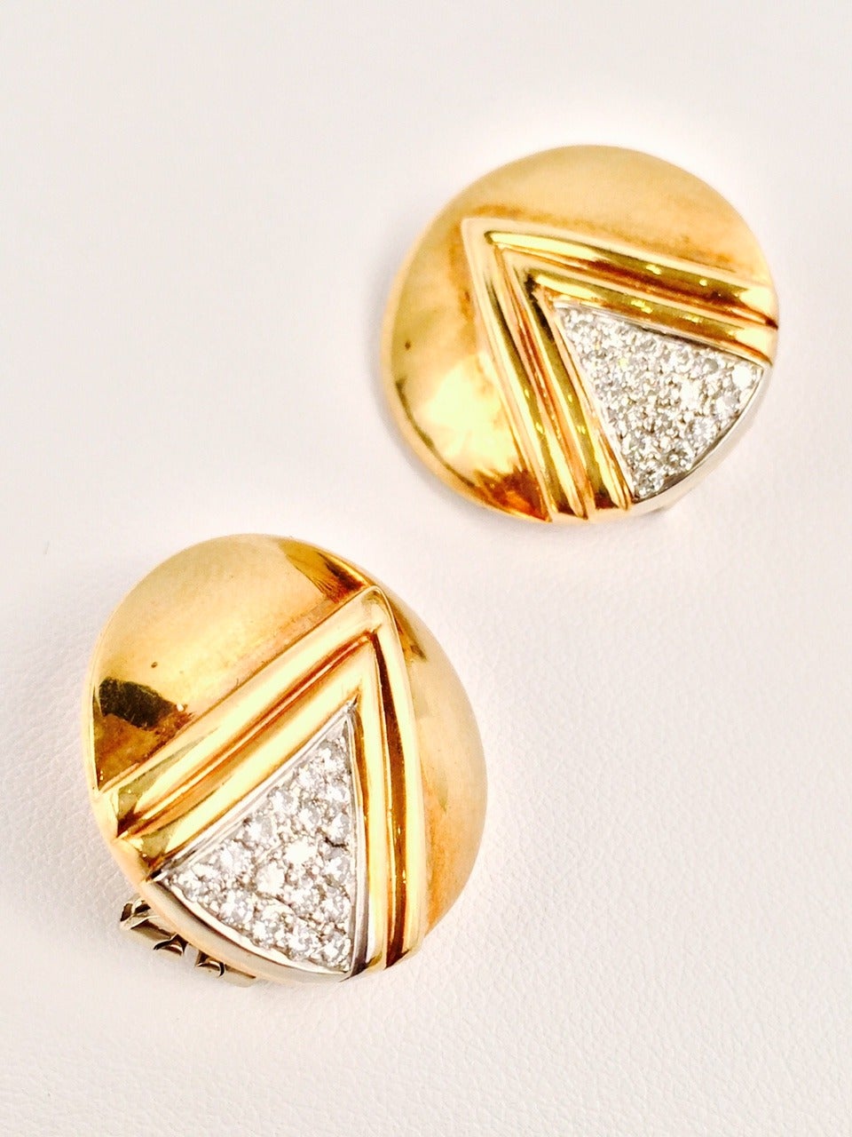 Exquisitely crafted from 18K yellow gold, these disc earrings evoke the dawn of the 1970's!  Features abstract and modern architectural design and white gold Omega backs.  Easily converted to clip on earrings!  Timeless and elegant.  Diamonds have a