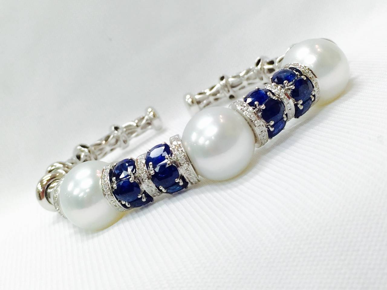 Meticulously crafted in 18K White Gold, this open end bangle bracelet is truly outstanding.  Pearls are an impressive 13.5 mm each with outstanding luster.  Easily AAA quality.  Oval Sapphires are beautifully matched and have a total weight of 5.30