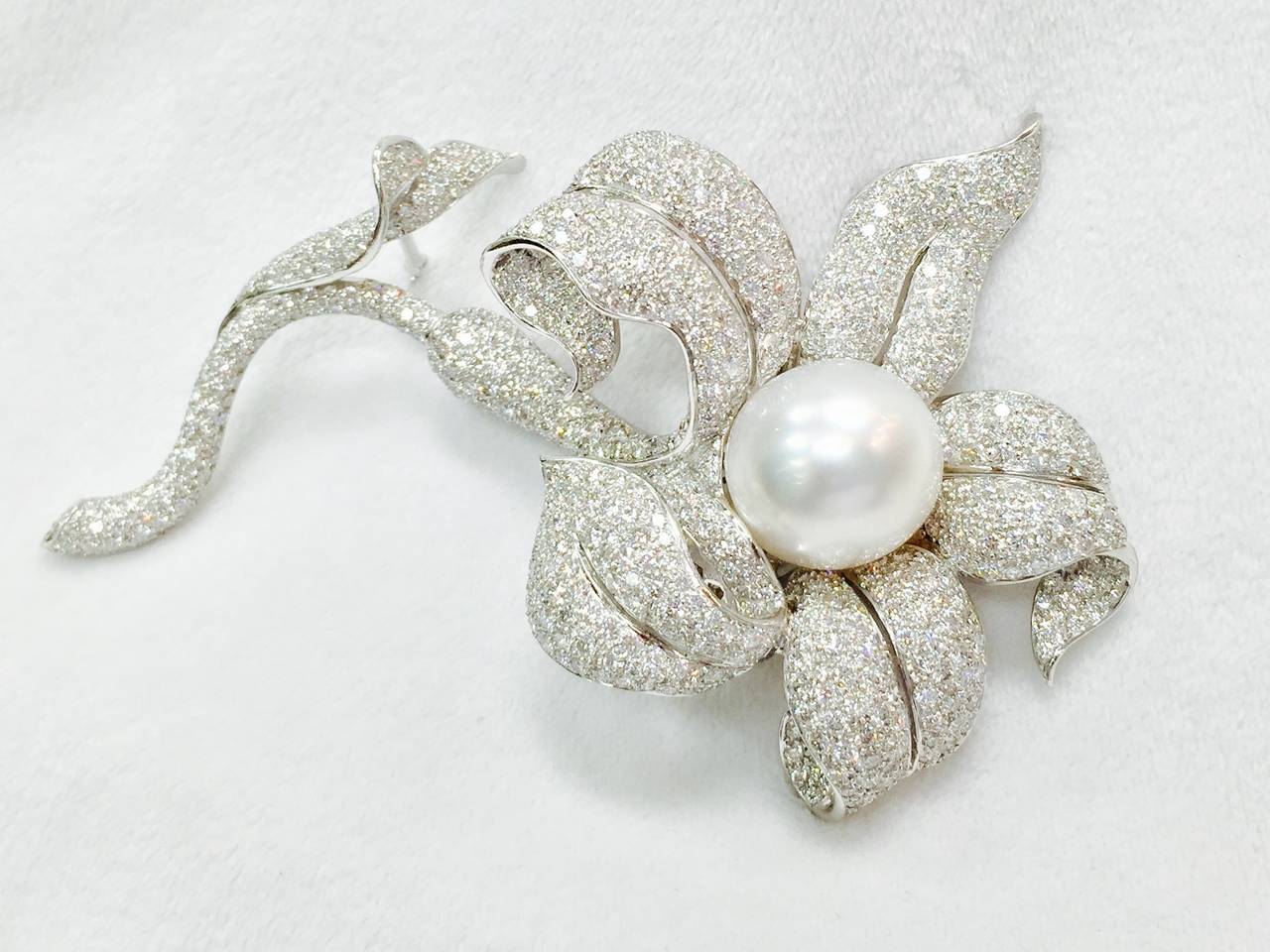 New White Diamond and Pearl Brooch artfully crafted in 18K White Gold.  The flower has incredible dimensional twists and curves.  Heavily encrusted with brilliant cut diamonds F/G color, VS1 clarity and 13.5 carats total weight.  A lustrous center