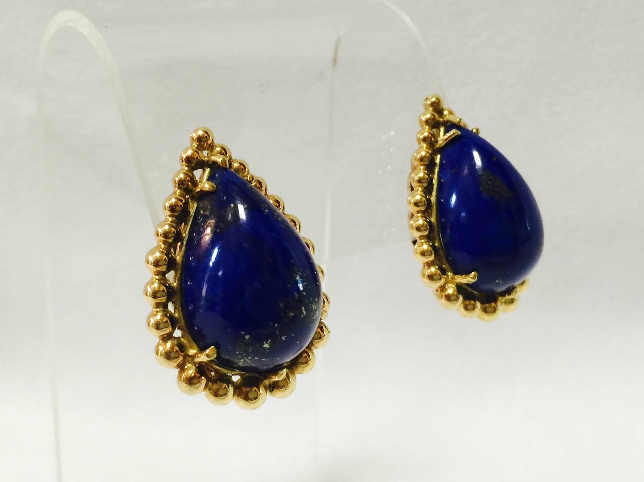 Classically beautiful earrings in 14K yellow gold will take you anywhere from day to evening!  The focal point are pear shape Lapis Lazuli stones in all their Ultramarine blue beauty.  Artfully framed in a bead border with pierced Omega backs, these