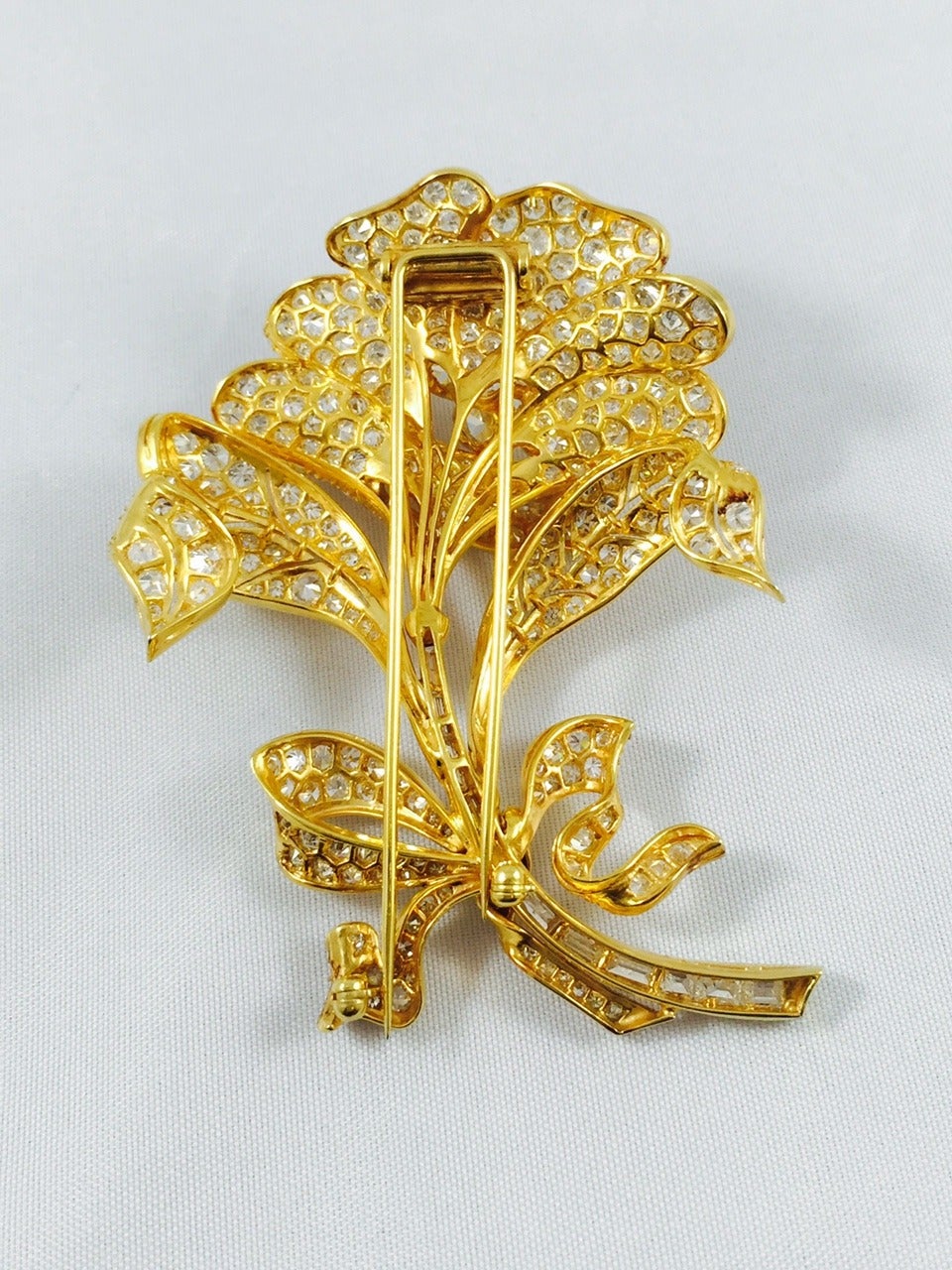 Visually exciting brooch fabricated in 18 karat yellow gold over platinum.  Sparkle abounds from every curved leaf, petal, bow and stem.  An outrageous 315 diamonds combine for an approximate total weight of 12.5 carats with G-J color, VS-I1