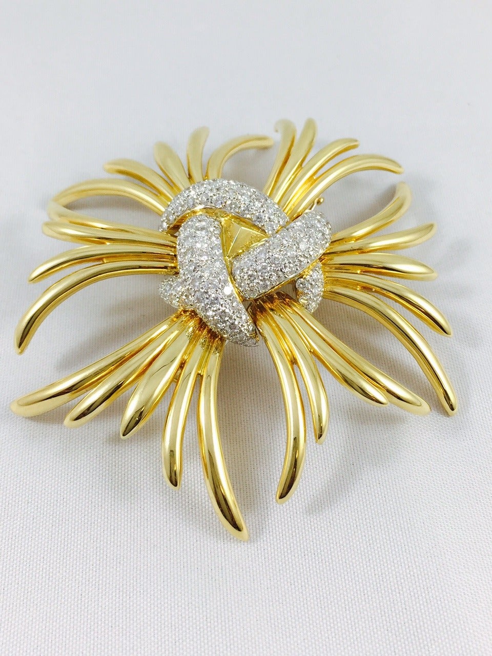 Beautifully bold 18 Karat Yellow Gold Starburst brooch is simply stunning!  A center featuring three curved, intertwining sections contain 150 pave set brilliant cut diamonds in 18 karat white gold. The diamonds, which weigh a hefty (approximately)