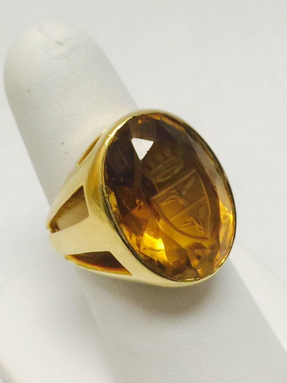 Beautifully crafted in 18 karat yellow gold, this ring features a faceted oval citrine measuring an impressive 14x20mm!  Carved symbols include a crown and two mythical birdlike creatures.  Ring is size 8 but can easily be resized up or down.  When