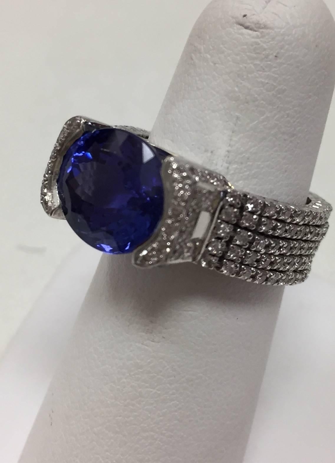 Larger tanzanites are getting harder to find!  This oval, east-west set, beauty weighs 7.34 carats.  A most unusual 18 karat white gold setting sets off the main stone to perfection.  Two diamond  bezels present the stone which is set in a diamond