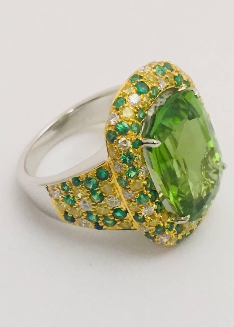 Striking, stunning statement ring!  Crafted in 18 karat white gold featuring a prong set, emerald cut faceted peridot with an impressive weight of 10.62 carats.  Peridot sits snugly in a frame of white diamonds, 0.53 ct tw, yellow diamonds, 2.70 ct