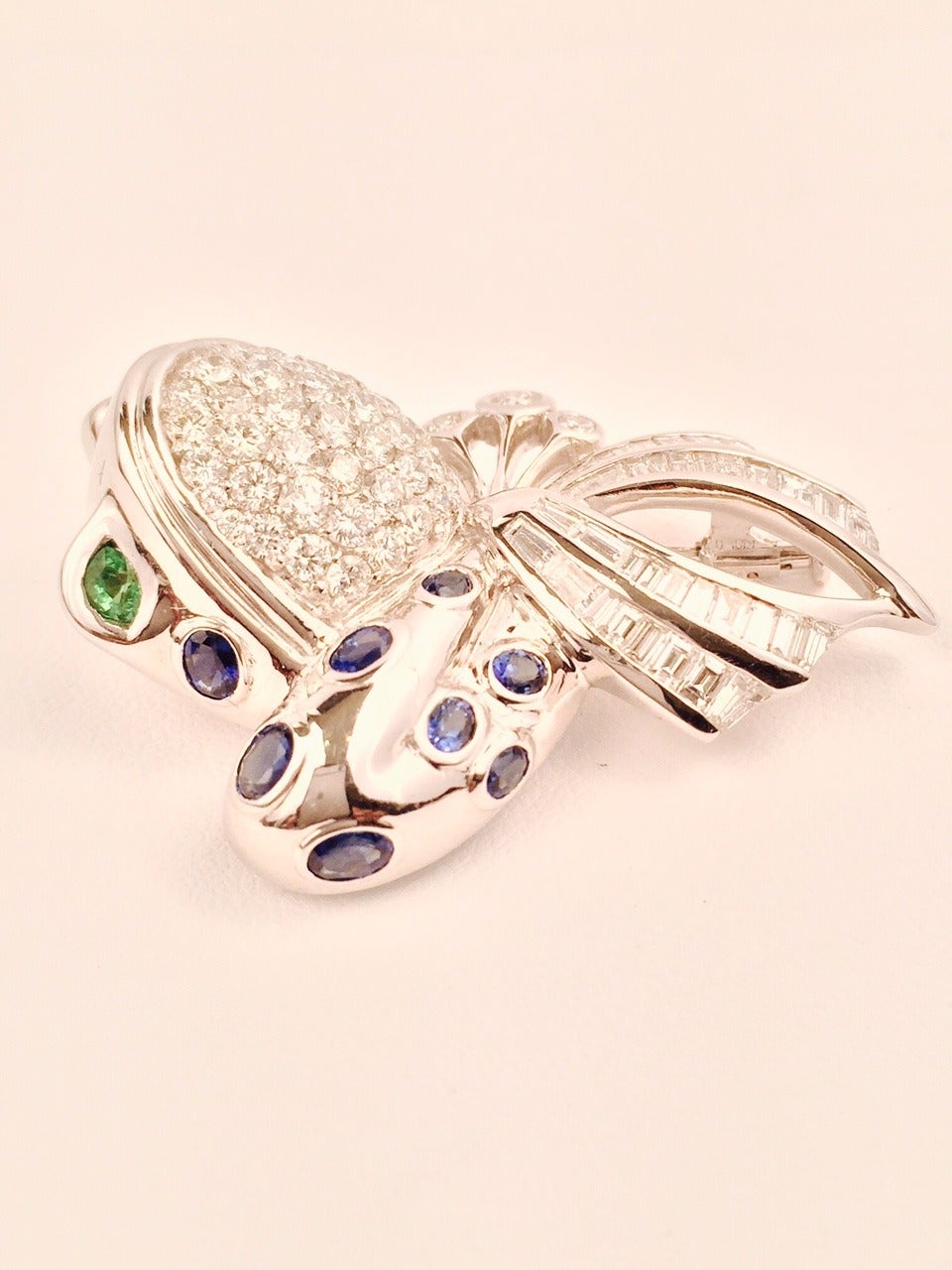 I8K White Gold Diamond and Sapphire Frog Brooch is a conversation piece!  Features Tsavorite eyes and bow shape.  Exquisite white diamonds are round and baguette shaped.  Crafted in the style of Marina B.  Made in Europe.