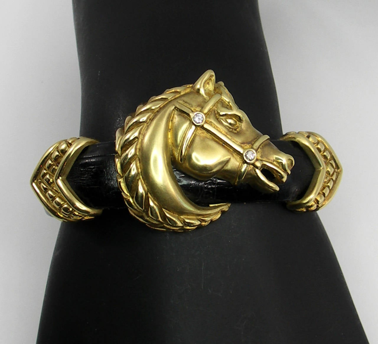 One ladies bracelet, comprised of a leather band, upon which 18K yellow gold motifs are attached. The center of the bracelet, is a satin finished horse's head, with high polished mane, and diamonds in the bridle. On either side of the horse are
