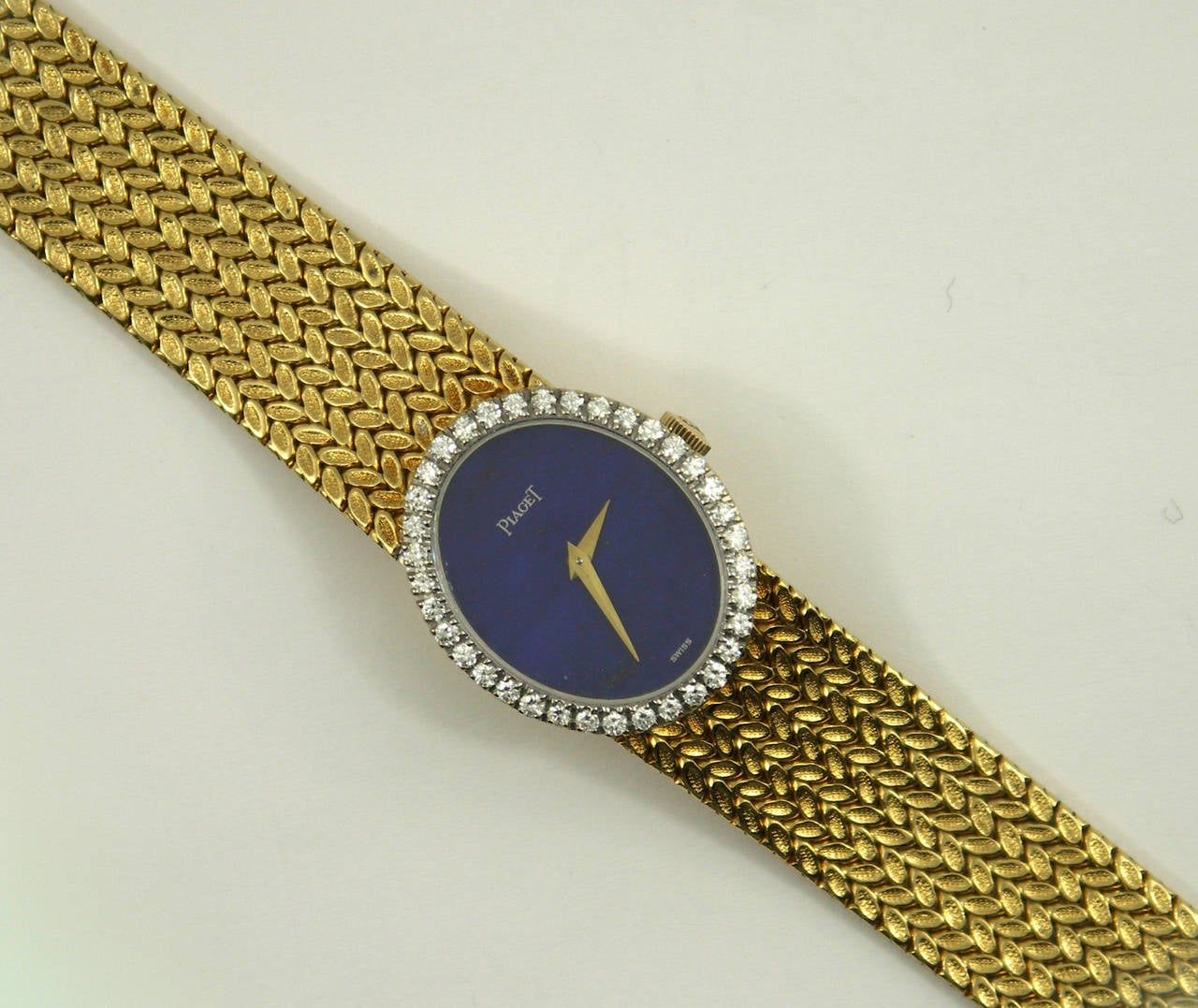 One ladies 18K yellow gold Piaget wristwatch, complete with Lapis Lazuli dial and diamond bezel. The case measures 2m long and 22mm wide, and is set with approximately 1ct of F/G color, and VS1 clarity diamonds. Overall length is 6 3/8 inches.