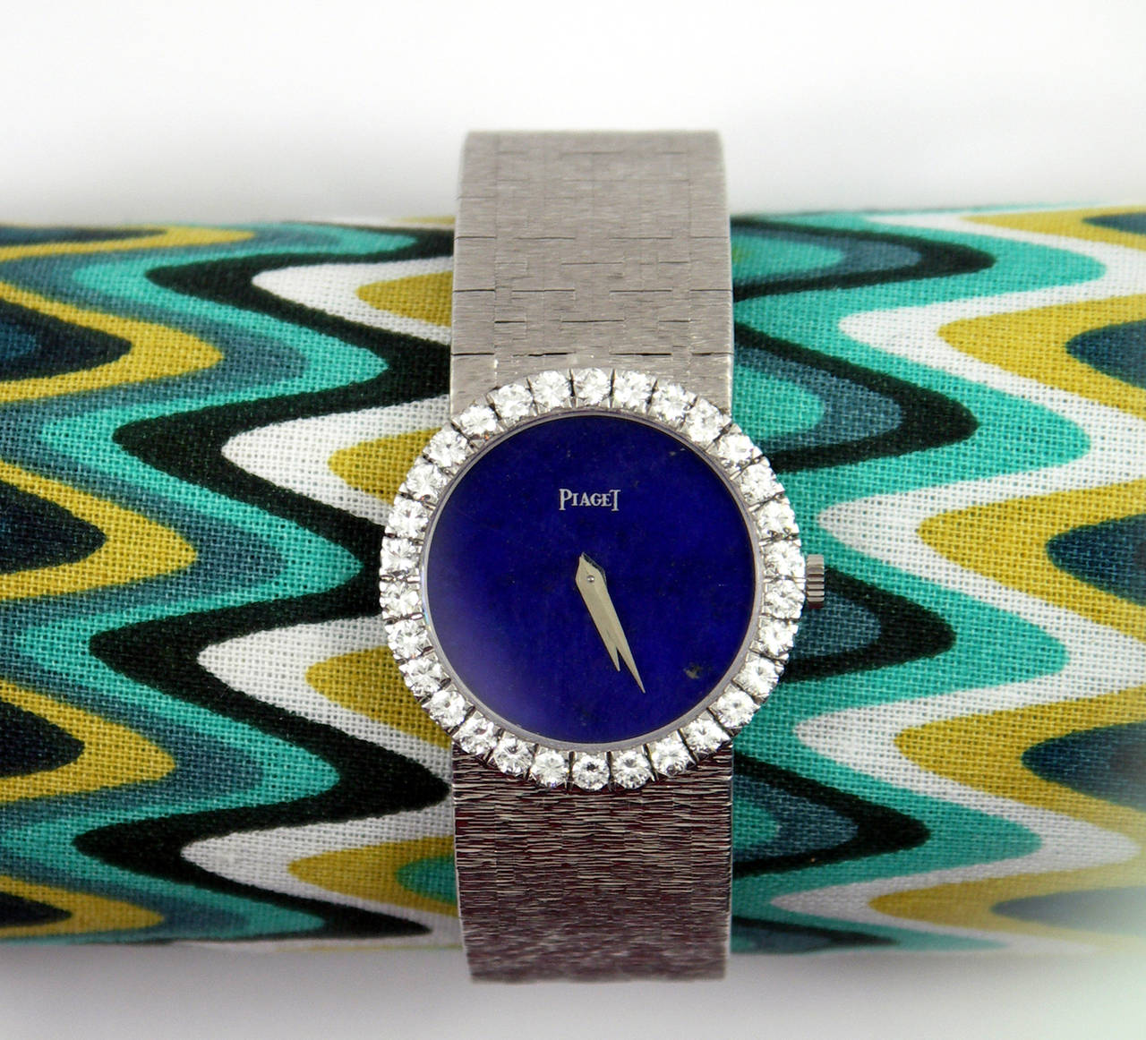 One lady's 18K white gold Piaget watch featuring a bezel measuring 25mm in diameter, and set with a total of approximately 1.66ct of round brilliant cut diamonds. The dial is a deep blue color Lapis Lazuli. The overall length is 6 1/2 inches.