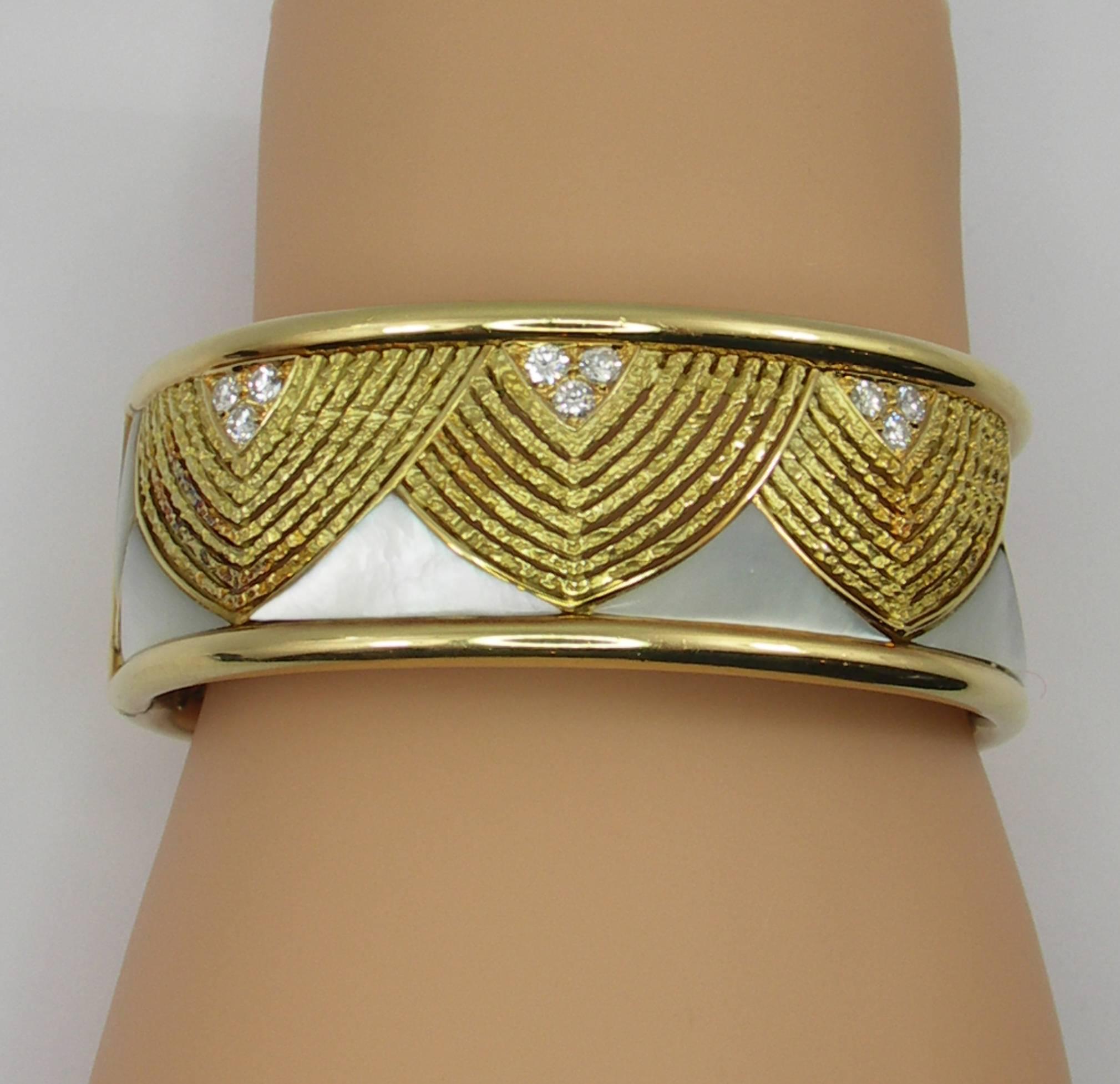 A ladies 18K yellow gold bracelet originally retailed by Neiman Marcus. Measuring 7/8 of an inch wide, it has a swagged design of filigree gold, contrasting with the mother of pearl. There are also 9 round brilliant cut diamonds weighing 1ct total