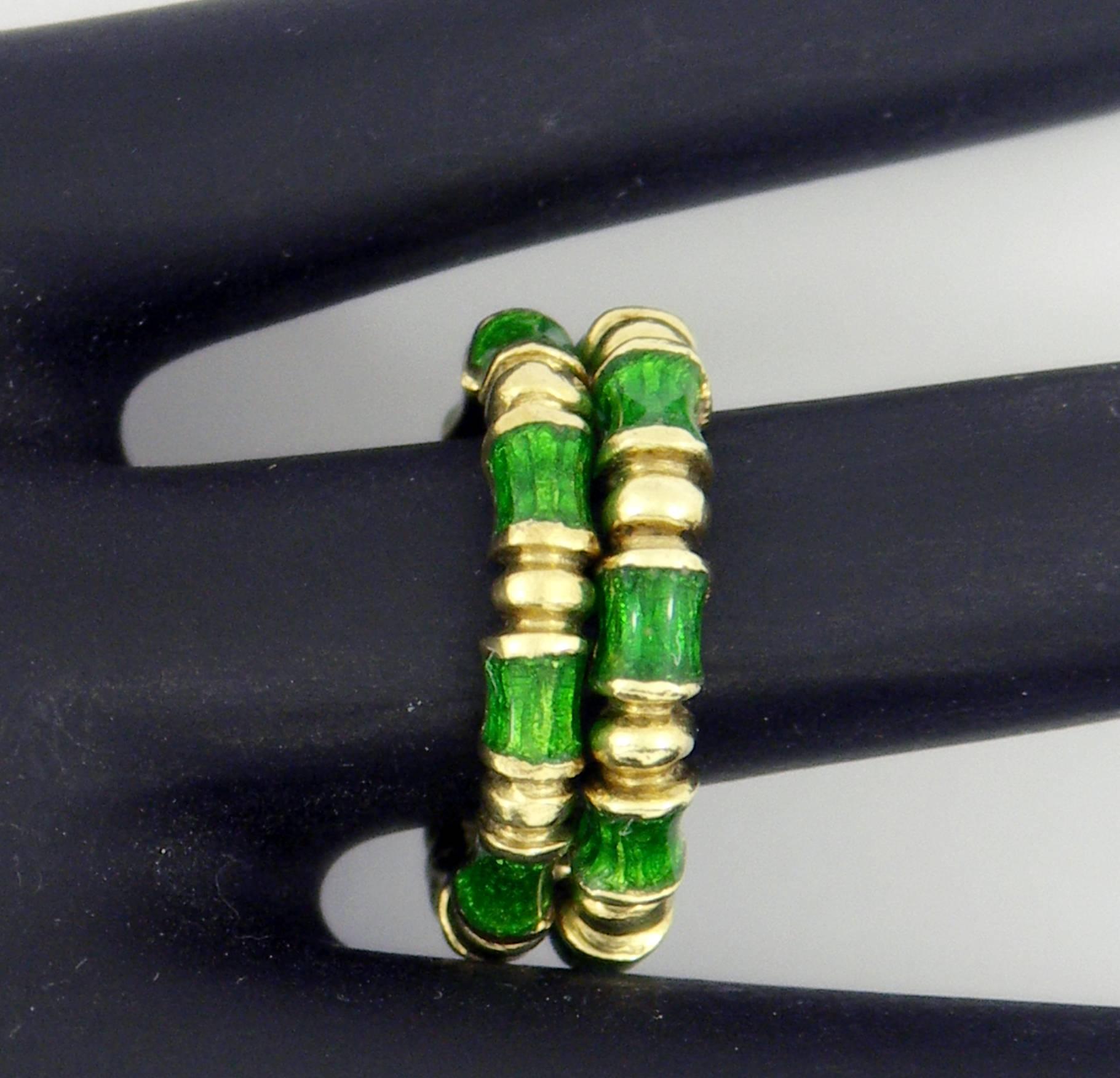 A pair of beautifully enameled band rings by Martine. Each of the rings measures 1/8 of an inch wide, featuring green enamel in between bamboo styled dividers. Size 5 1/4
