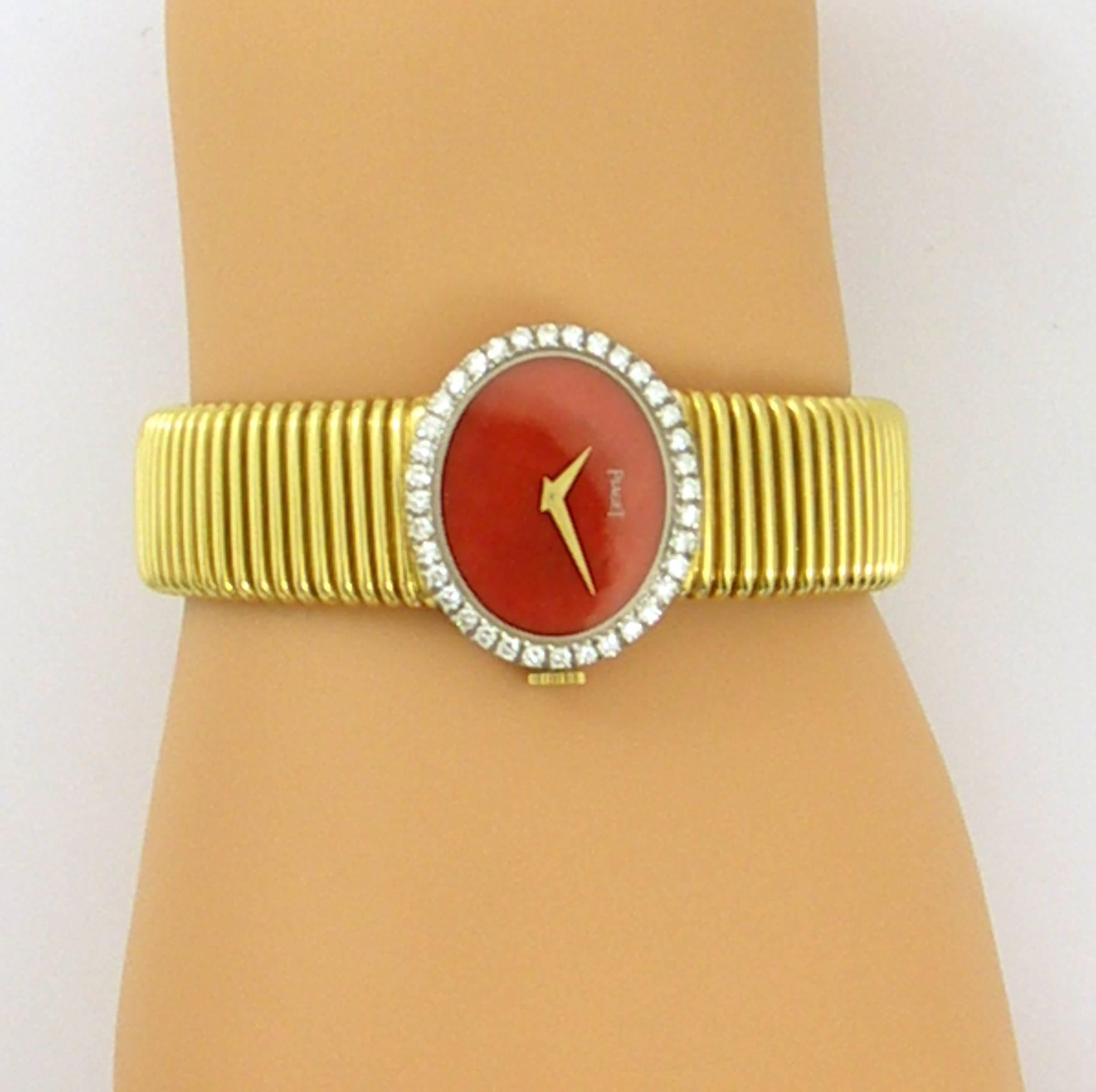 An 18K yellow gold, ladies Piaget wristwatch with coral dial. The case measures 7/8 of an inch long, and 1 1/16 of an inch wide, and is set with approximately 1.10ct of round brilliant cut diamonds. Diamonds are of overall F color and VVS2/VS1