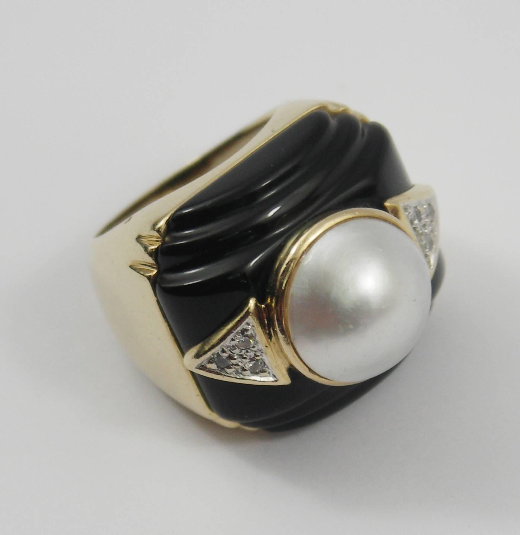 A 14K yellow gold ring centering one mabe pearl measuring 13mm, flanked by triangular motifs set with a total of 6 diamonds approximately 0.10ct total weight, above geometric fluted black onyx. Size 6.  Weight 17 grams.