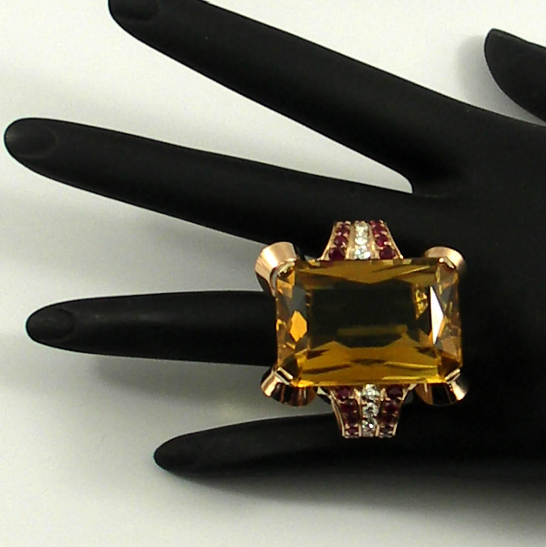 A 14K yellow gold ring set with one rectangular scissors cut citrine weighing approximately 54ct, accented on either side by two rows of rubies, and one row of diamonds. Diamonds weigh 0.50ct total approximate weight, and rubies weigh 1ct total