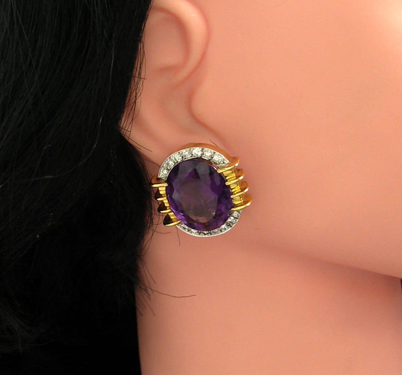 A modernistic pair of 18K yellow gold earrings, signed MB. Each earring is centered around an approximately 20ct faceted oval amethyst, flanked by retro style on the left and right; and by pave' set diamonds on the top and bottom. Overall diamond