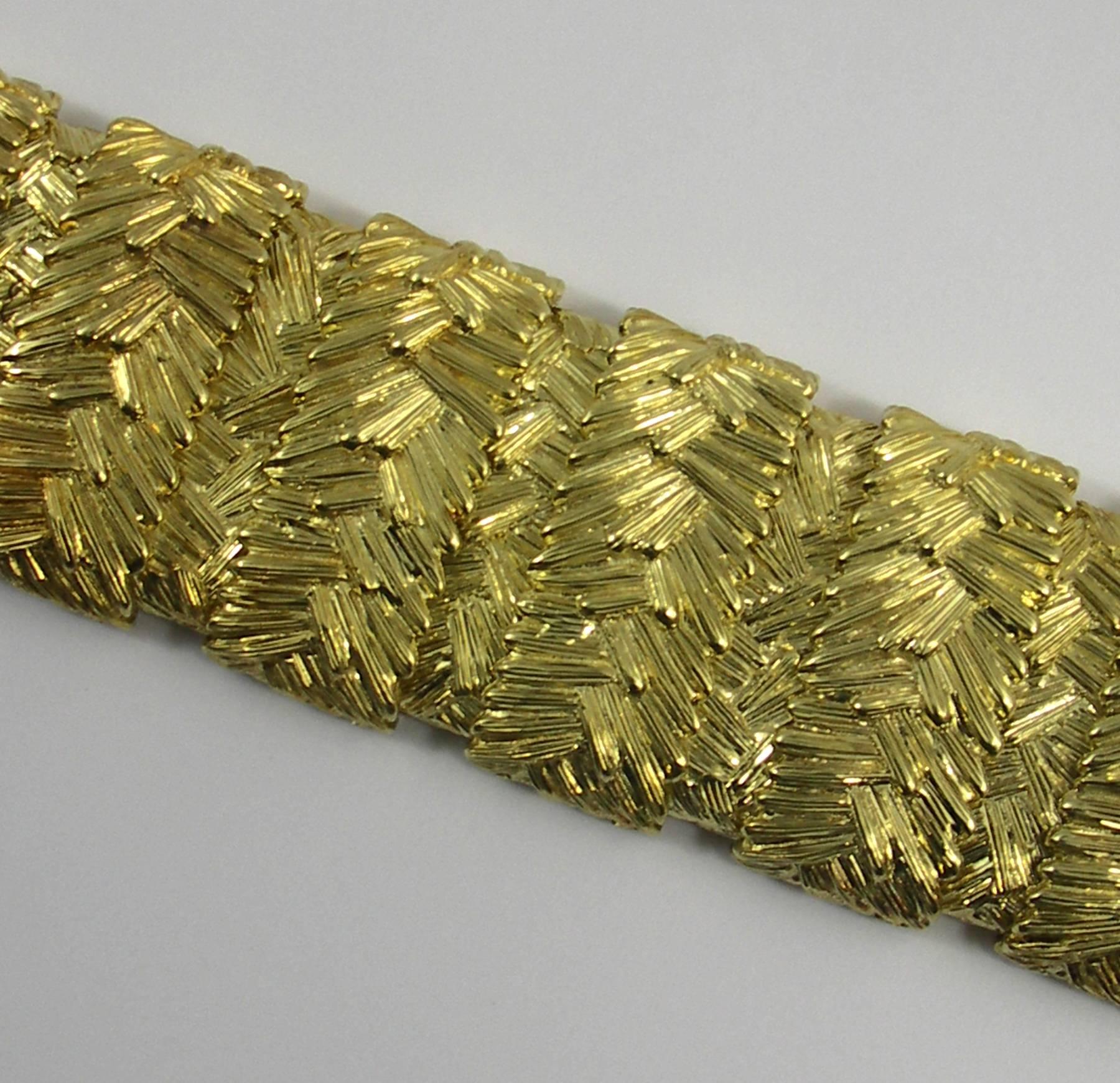 An 18K yellow gold bracelet, measuring 1 1/2 inches wide, and comprised of highly textured, track-like links, in order to create a cuff-like fit. Inside circumference is 6 1/4 inches. 