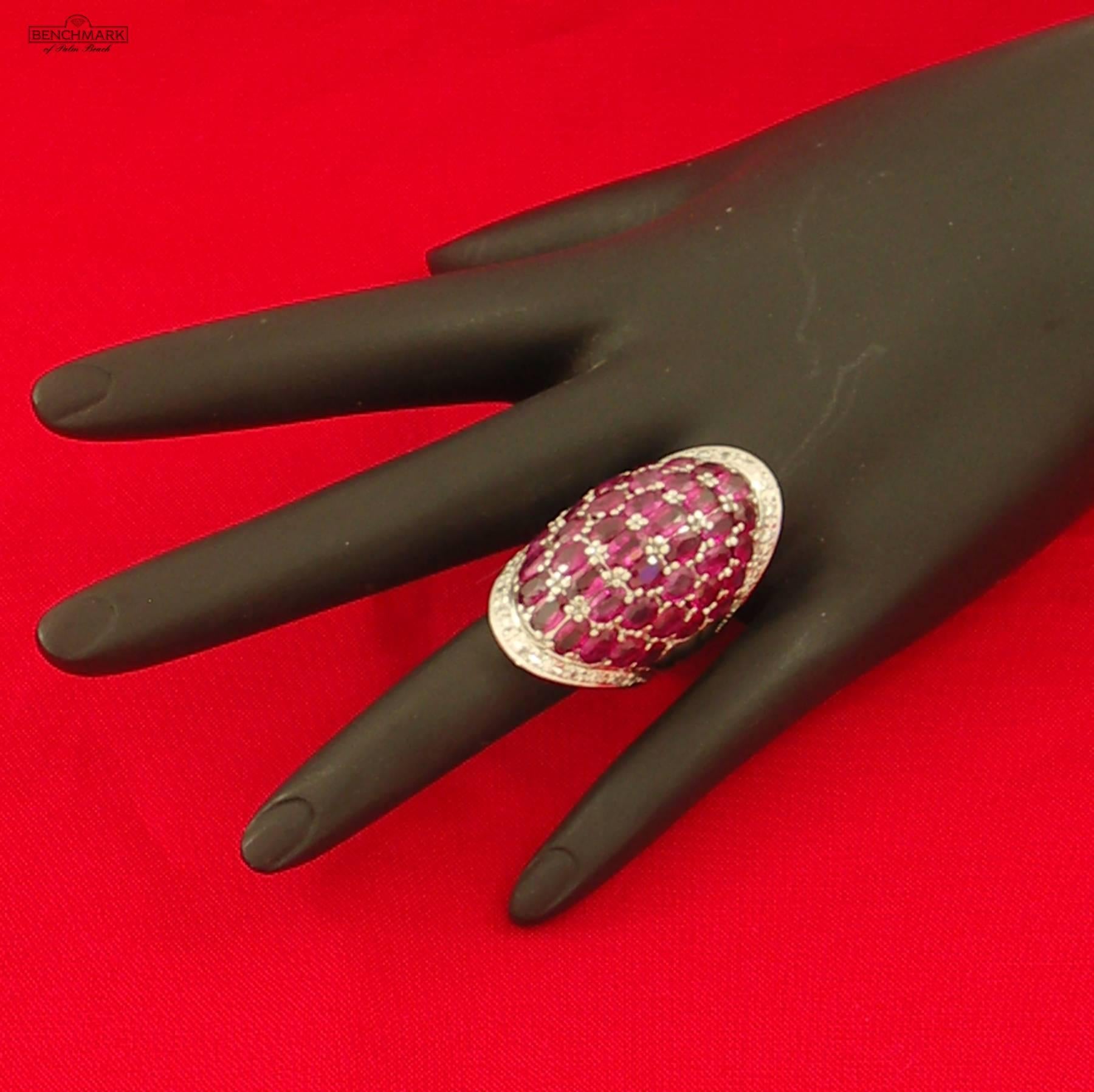  A beautifully contoured platinum ring set with assorted oval, faceted rubies weighing a combined weight of approximately 12.33 carats with even saturation and  medium tone. Accenting the ruby are assorted round brilliant cut diamonds weighing