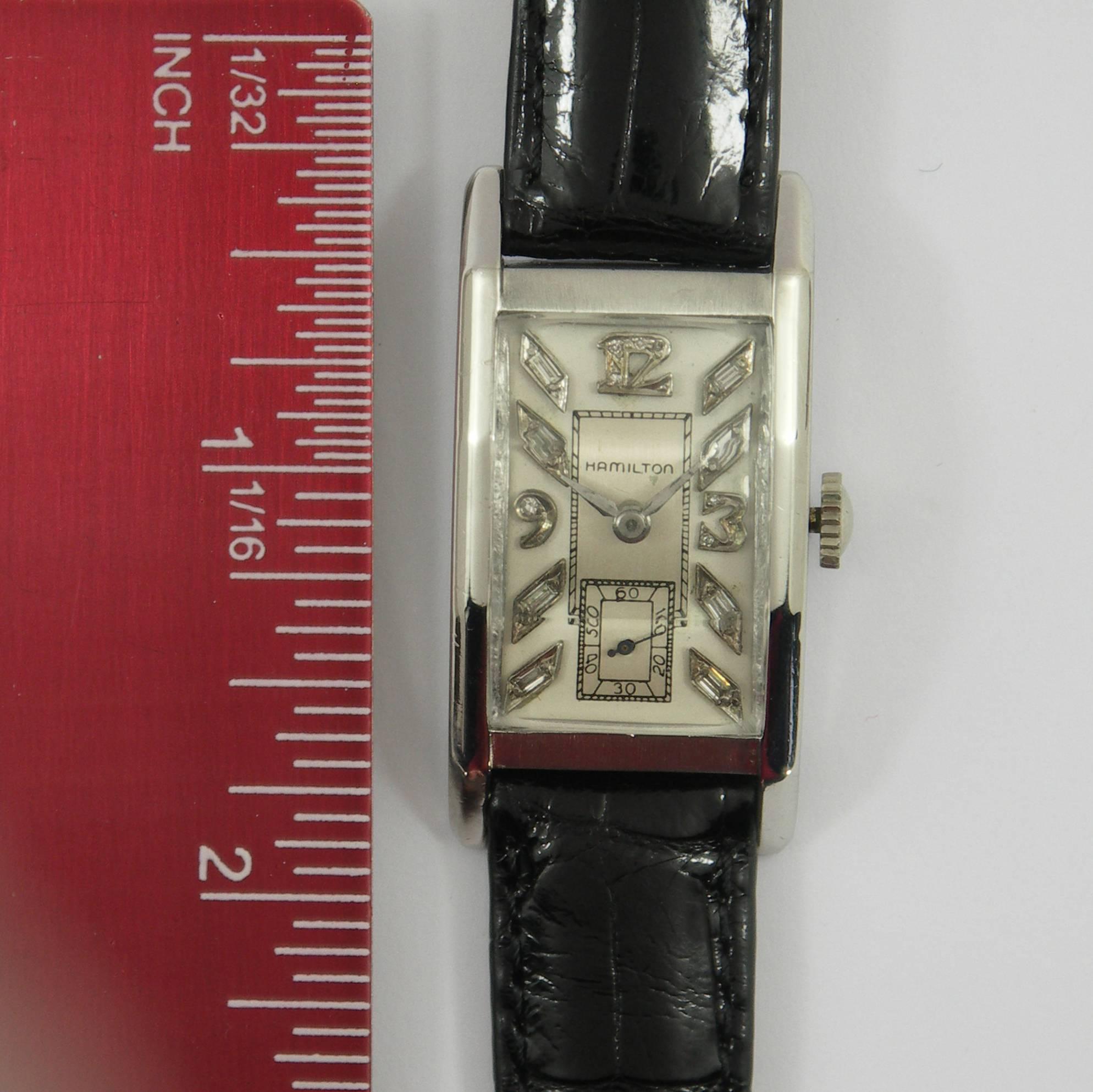 A classic Platinum wristwatch by Hamilton, with a case measuring 35mm X 20mm, and an Art Deco Dial with Diamond markers and numbers. Watch features a new, black, American alligator band with white metal buckle.  