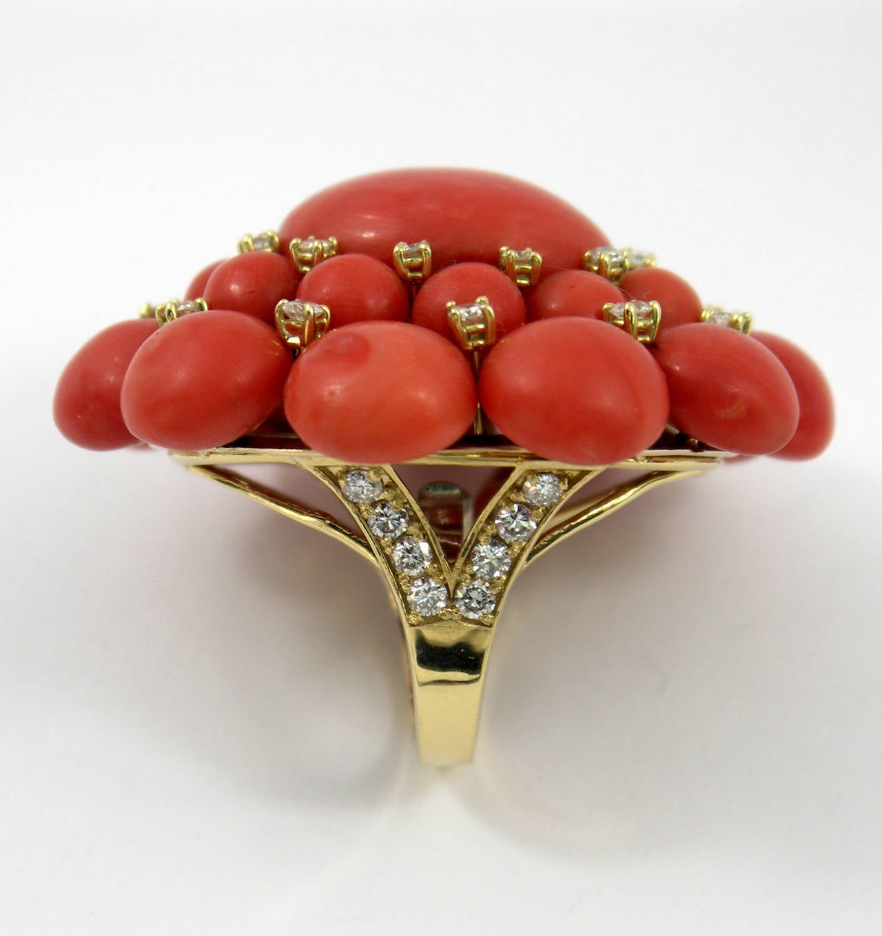 A ladies ring comprised of a 14K yellow gold upper portion, with 18K yellow gold shoulders and shank. The design area measures 2 1/4 inches long and 2 inches wide, and is embellished with 22 round cabochon corals, and one oval cabochon coral