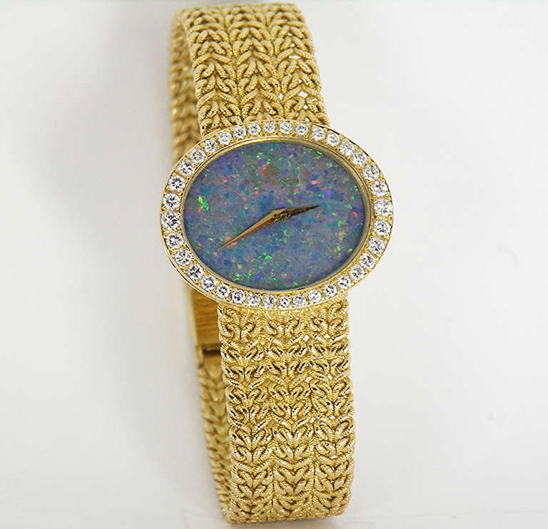 This Bucherer lady's 18k yellow gold oval bracelet watch with diamond bezel and black opal dial measures 25mm across by 20.5mm top to bottom. The beautifully set diamond bezel contains an approximate total of 1.35 cts. of round brilliant cut