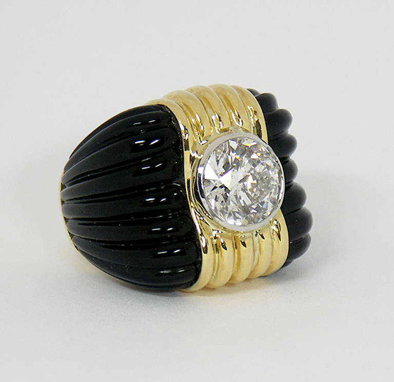 Made by Charles Turi, this massive,unisex 18K yellow gold ring is flanked 
by two sections of fluted onyx. Bezel set in the center of the ring is an EGL certified 4.50CT round brilliant cut diamond of E Color and SI2 Clarity. 
From left to right,