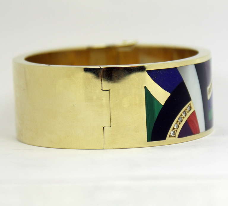 One ladies 14K yellow gold bangle bracelet, featuring beautifully inlaid stone work, for which Asch Grossbardt is known. The assortment of gemstones include coral, lapis lazuli, malachite, mother of pearl, and onyx, each stone masterfully cut and