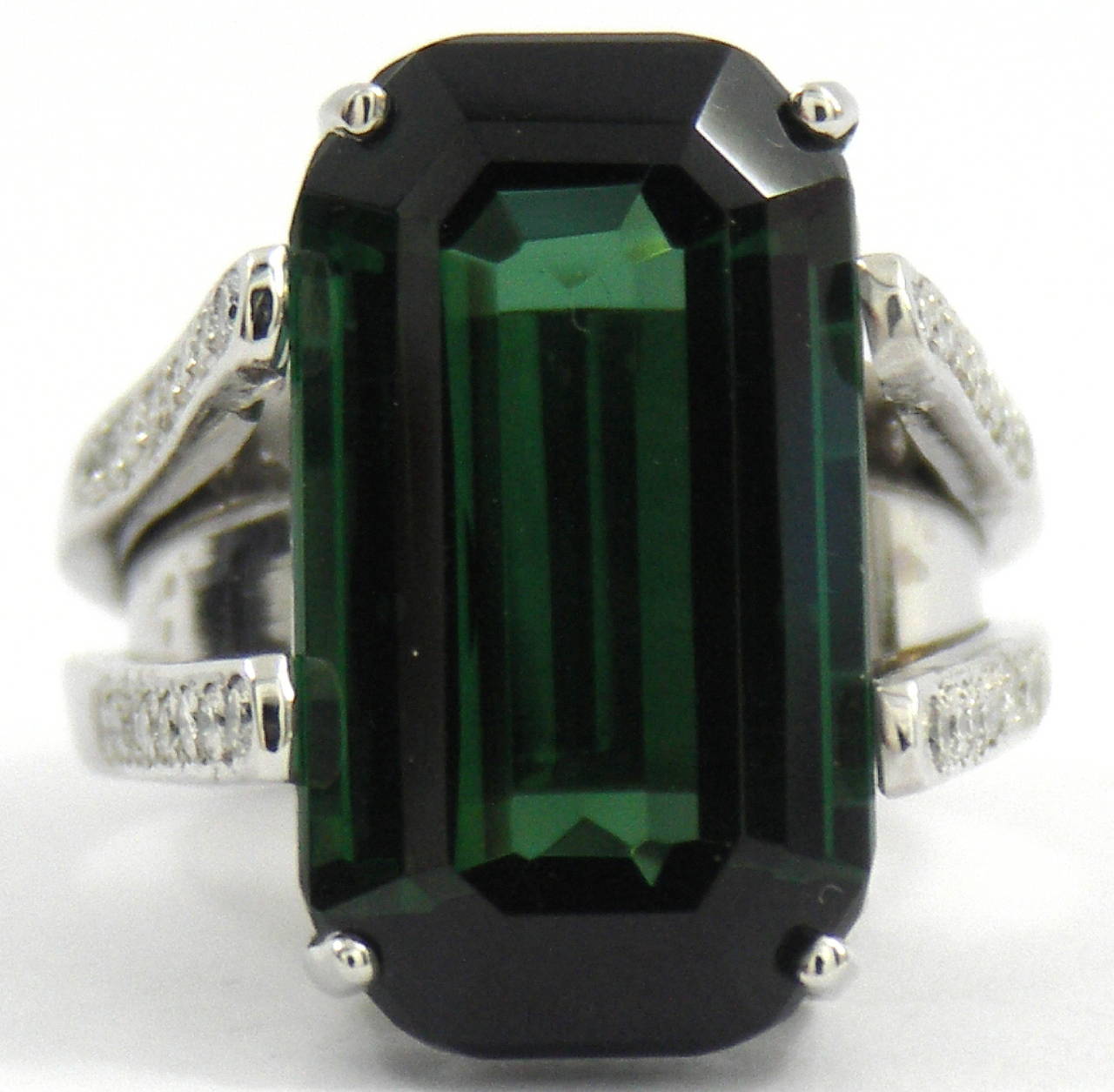 A split-shouldered platinum ring set with 32 round brilliant cut diamonds for a total approximate weight of 0.75ct. The center stone is a beautifully balanced, emerald cut, green tourmaline weighing 22.15ct.