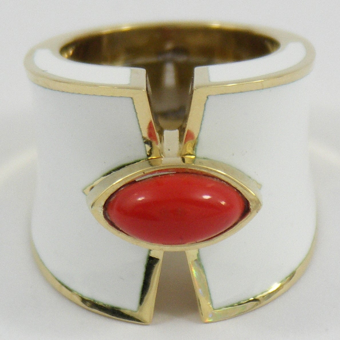 One 18K yellow gold ring with a cigar band design. Its split front is connected by a navette shaped bezel, set with a coral, measuring 11mm X 6mm. Ring is a size 6 1/2