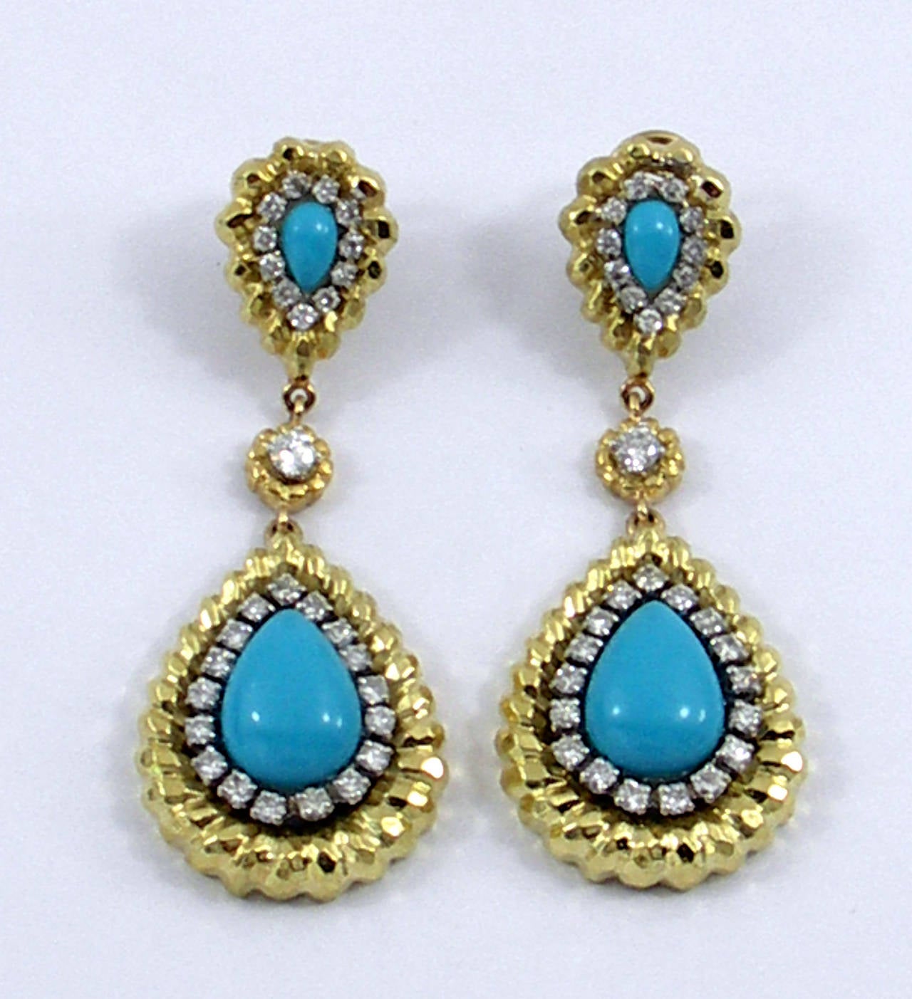 A pair of 18K yellow gold earrings, measuring 2 5/8 inches long. The top of each earring is set with a pear shaped turquoise measuring 5mm X 8mm, and the bottom of each earring has a 11mm X 16mm turquoise. These beautiful earrings are set with