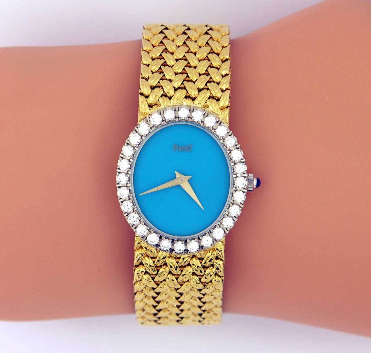 One ladies Piaget wristwatch, with an amazing, robin's egg, turquoise dial. The dial is surrounded by a bezel measuring 27mm long, and 24mm wide, and is set with a total of 1.25ct of round brilliant cut diamonds. The woven band is beautifully
