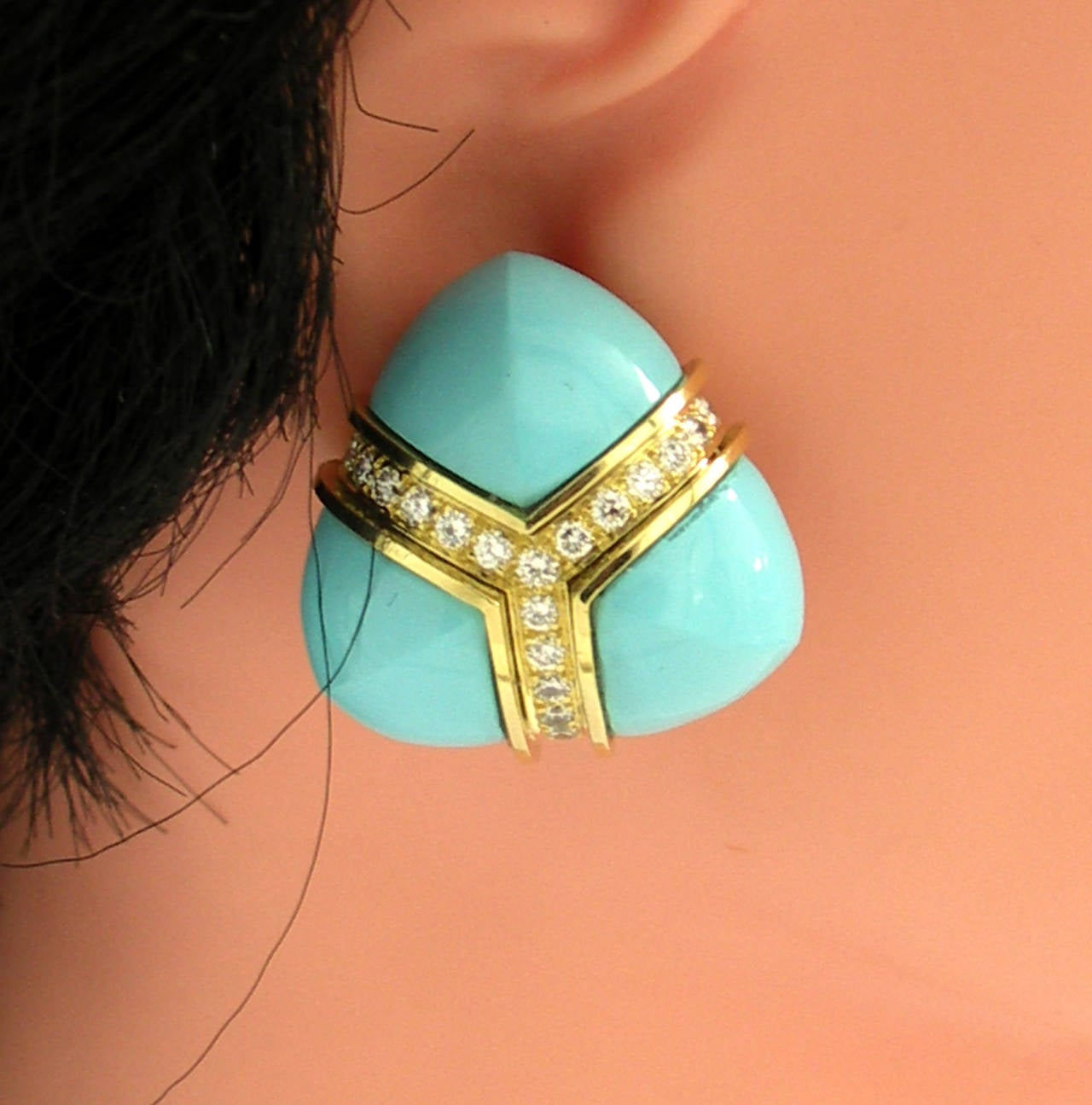 A pair of 18K yellow gold earrings, with a triangular design. Each earring is set with three custom carved turquoise. Separating the turquoise is A 