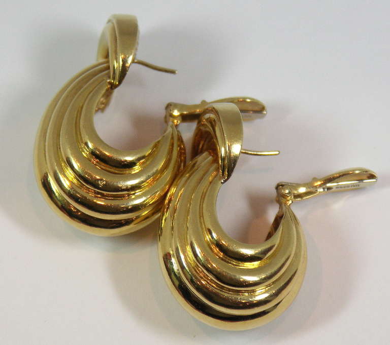 A pair of 18K yellow gold earrings of a grand scale. The earrings feature a contoured top measuring 3/4 of an inch wide, with a flowing design that cascades down. The overall length is 1 1/2 inches, which is combined with a depth of 3/4 of an inch,