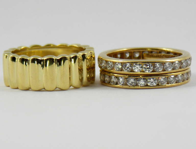 One pair of 18K yellow gold, channel set eternity bands by Tiffany & Co, flanking a beautifully high polished 18K yellow gold band also by Tiffany & Co. Each diamond band is set with approximately 1ct of overall F color and VVS2/VS1 clarity, round
