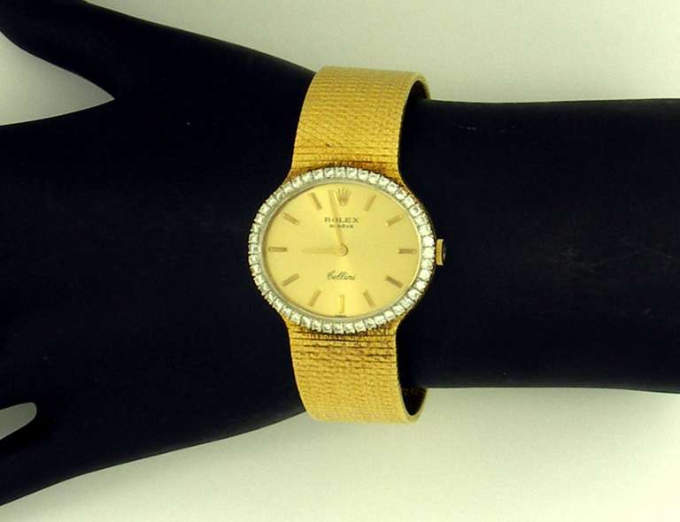 Rolex lady's 18k yellow gold Cellini bracelet watch set with approximately 0.75 cts. of round brilliant-cut diamonds to the bezel, which measures 1 1/8 inch wide, and 15/16 of an inch long. The overall length of this bracelet is seven inches.